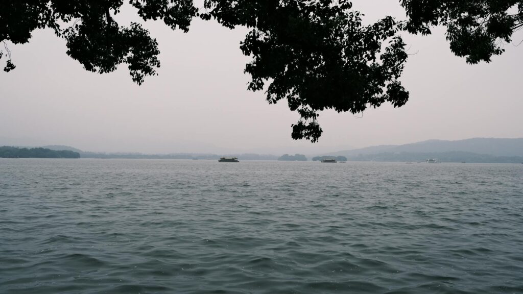 Hangzhou West Lake with boats and pagoda surrounded by mountains on a day trip from Shanghai
