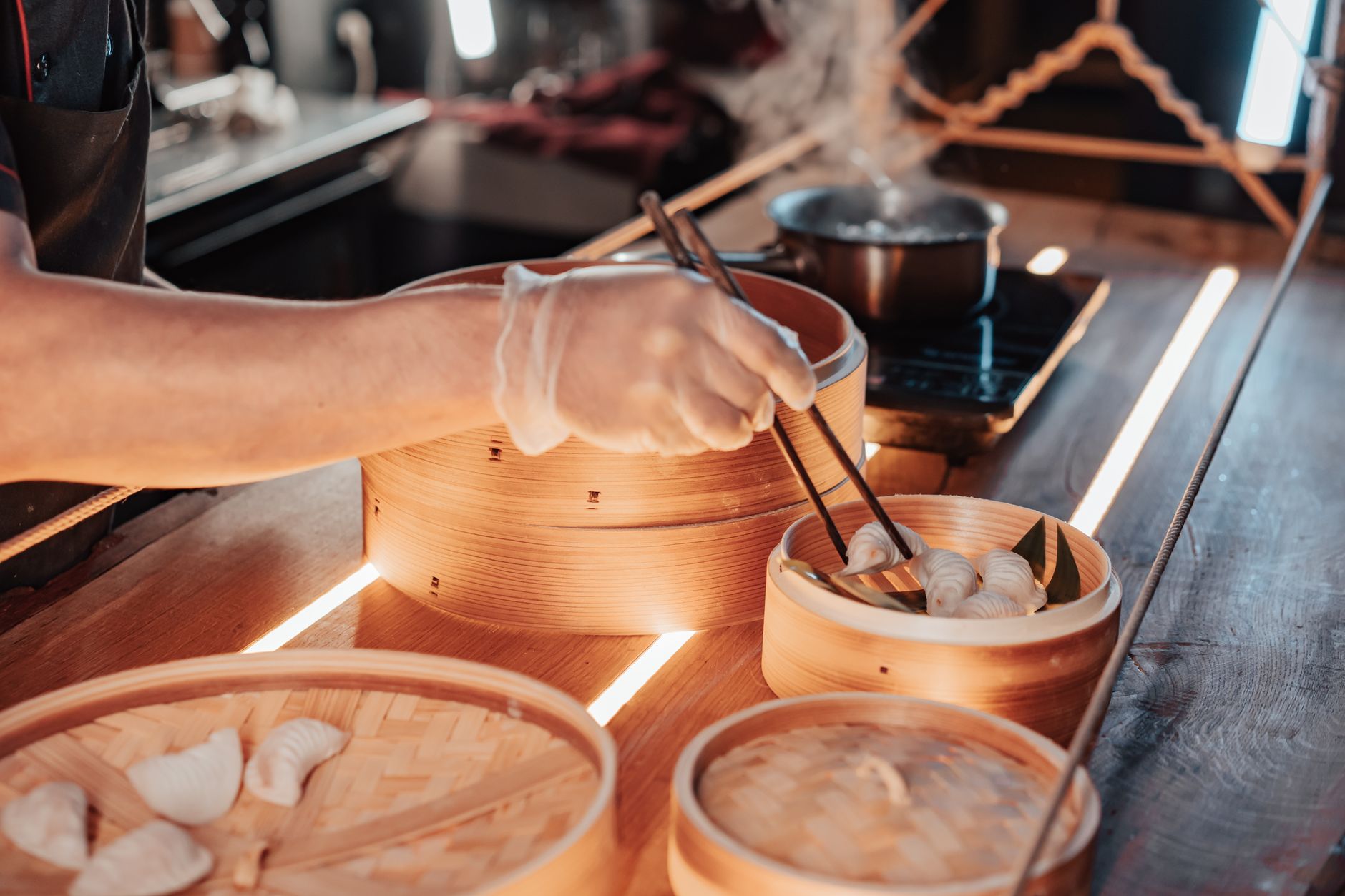 Chopsticks lifting a Shanghai xiaolongbao from a bamboo steamer onto a spoon to sip the soup