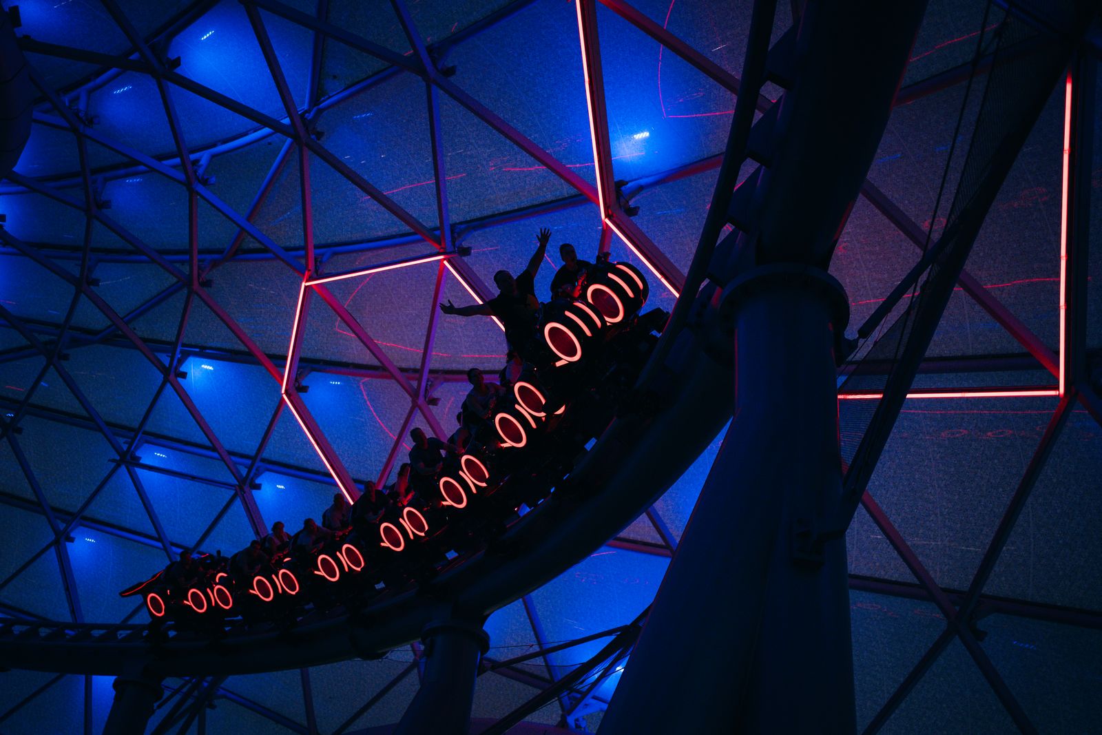 Neon-lit roller coaster at night, evoking the TRON Lightcycle Power Run at Shanghai Disneyland