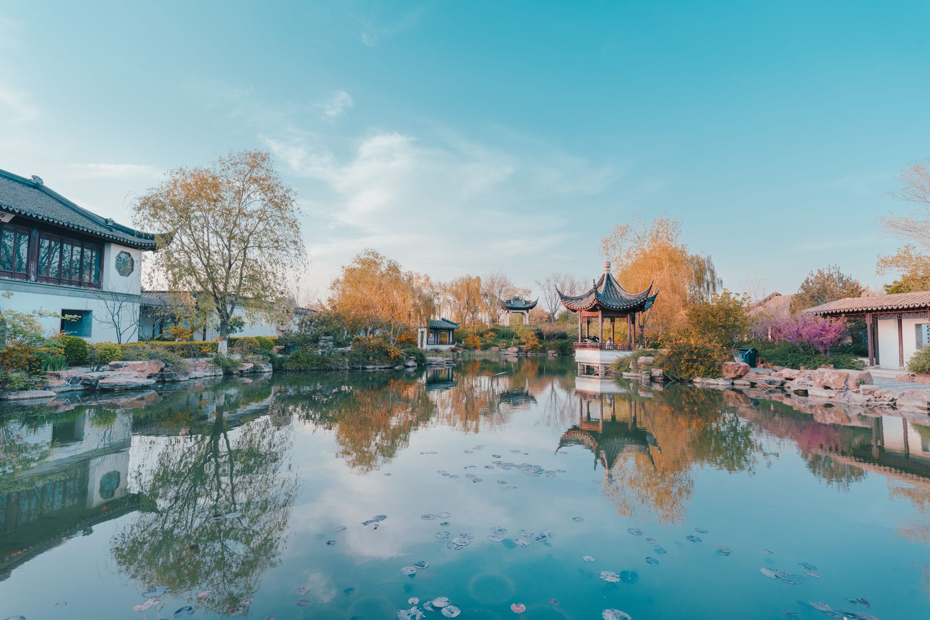 Classical Chinese garden pavilions reflected in a calm pond in autumn, in the Jiangnan style of Yu Garden Shanghai
