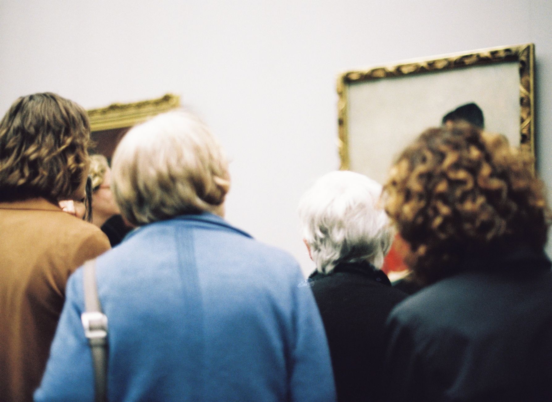 Visitors looking at framed paintings in a museum gallery in Shanghai.