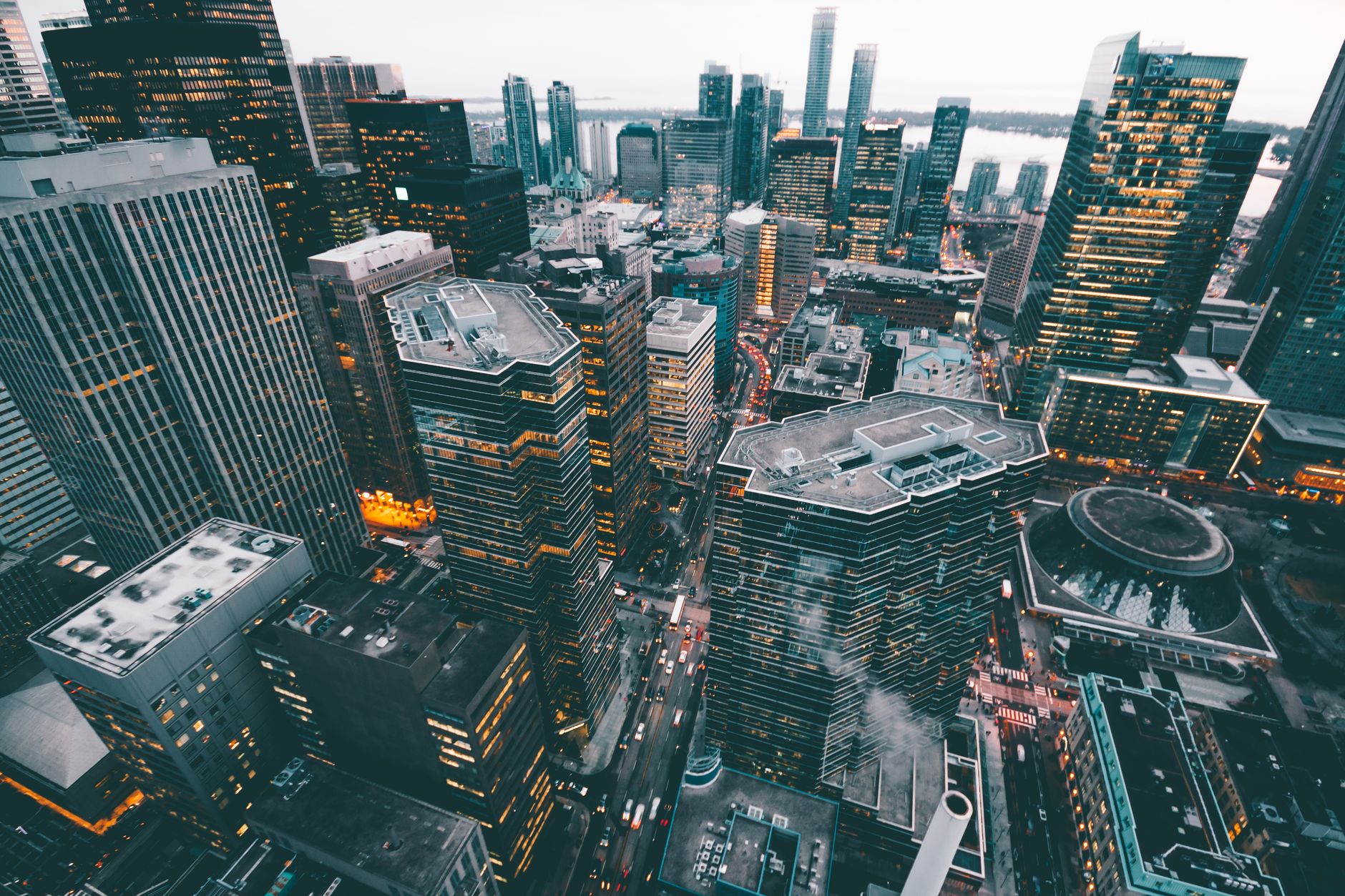 High-angle view over a dense city of skyscrapers with lights coming on at dusk
