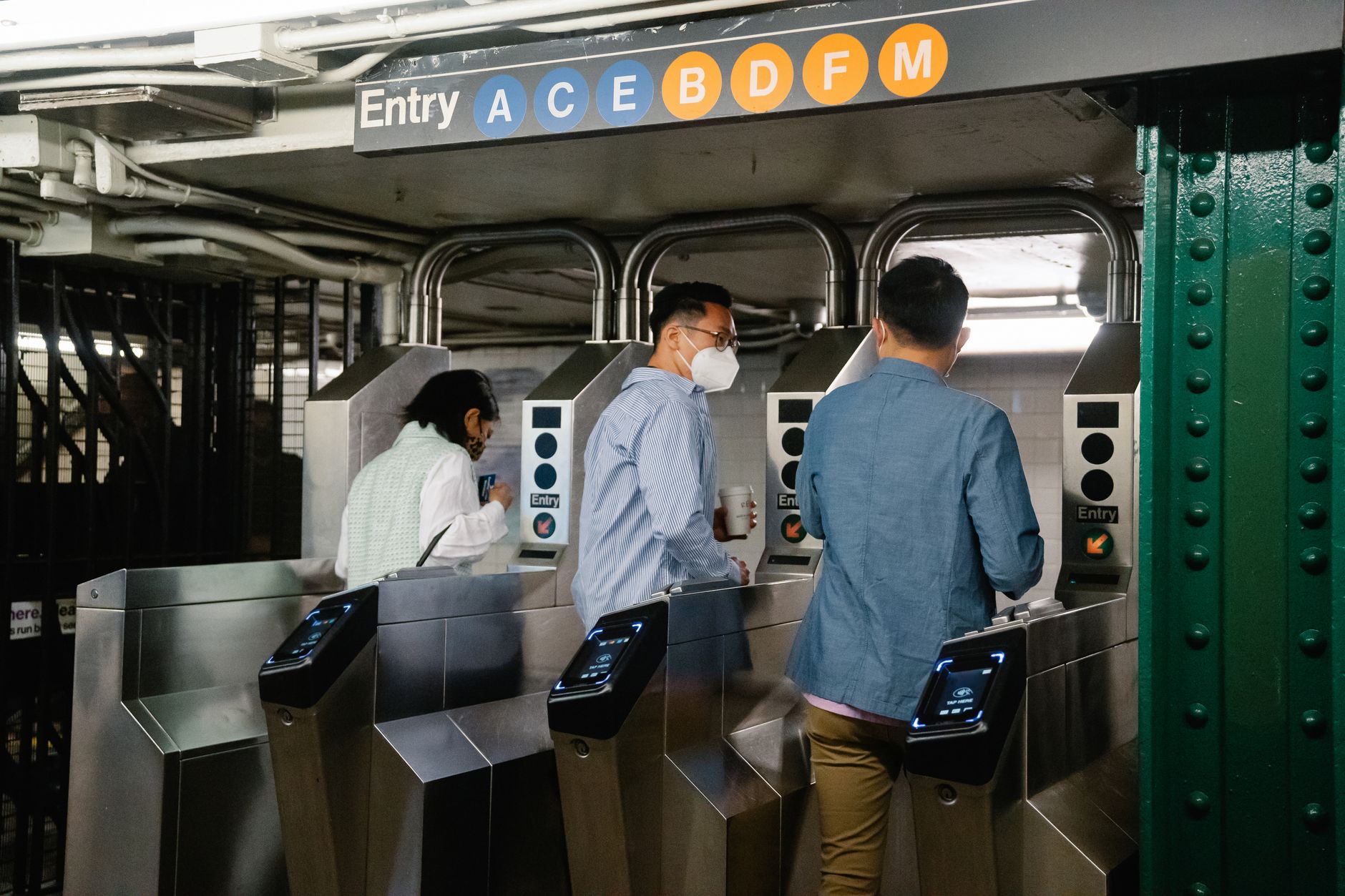 Passengers passing through metro station ticket gates in a busy city