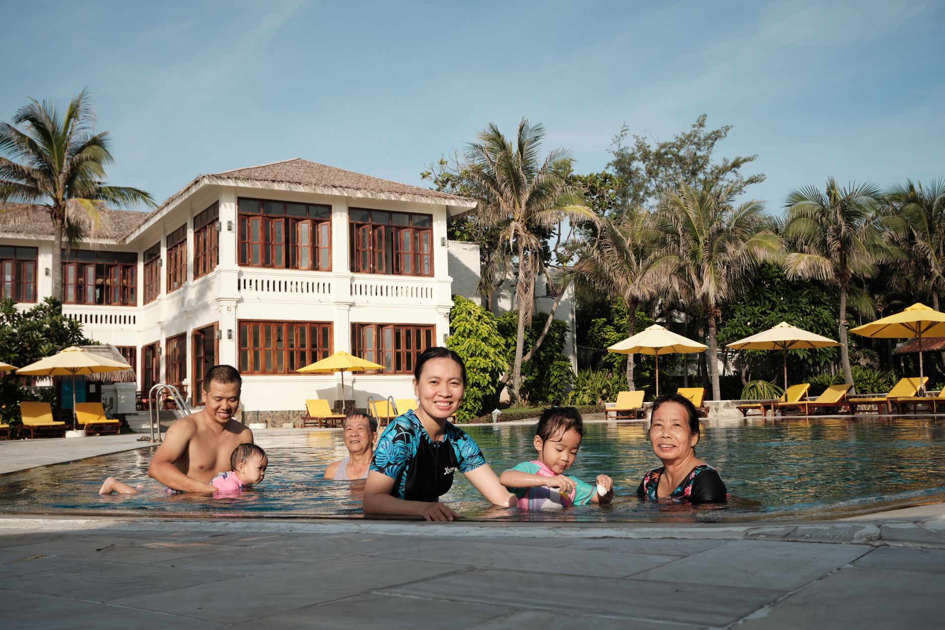 A family relaxing beside a hotel swimming pool on a sunny afternoon