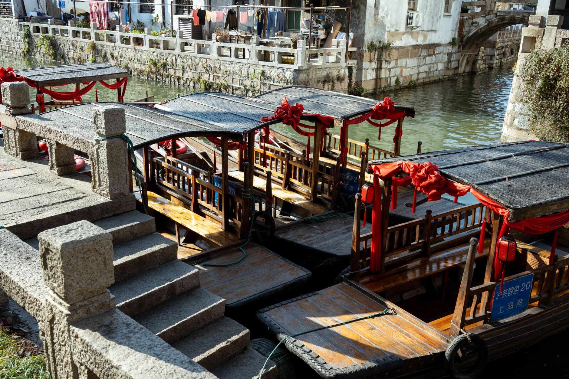 Traditional wooden canal boats with red awnings moored on a historic waterway near Shanghai