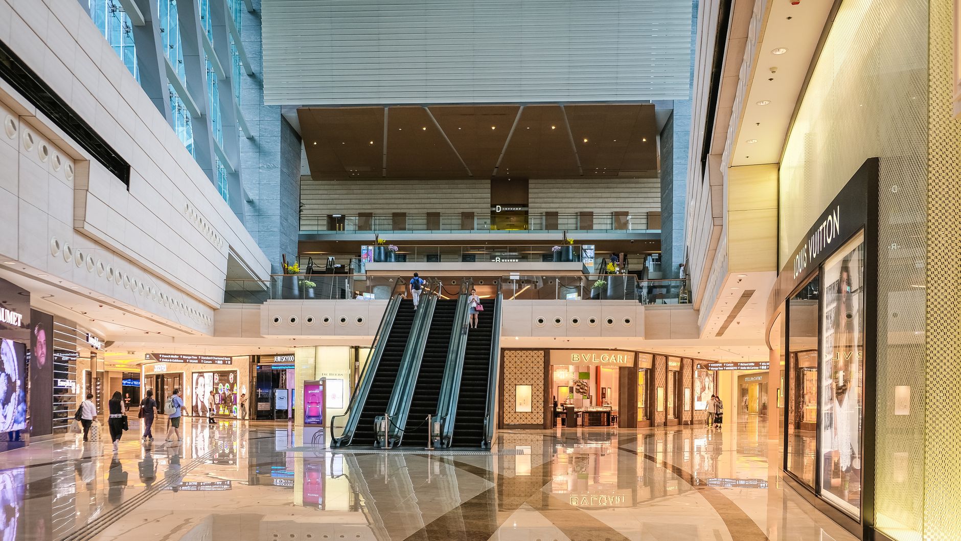 Multi-level atrium of an Asian luxury shopping mall with escalators and designer stores