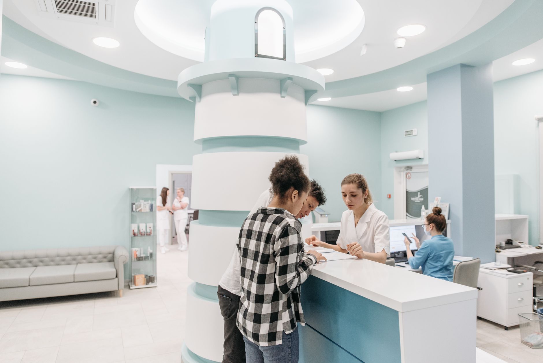 Patients registering at a clinic reception desk in a modern hospital