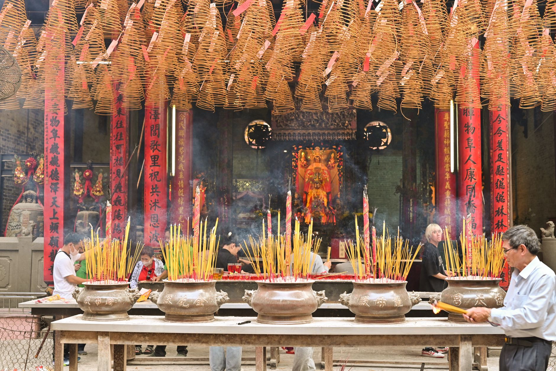 Incense smoke drifting through a Chinese temple hall filled with worshippers