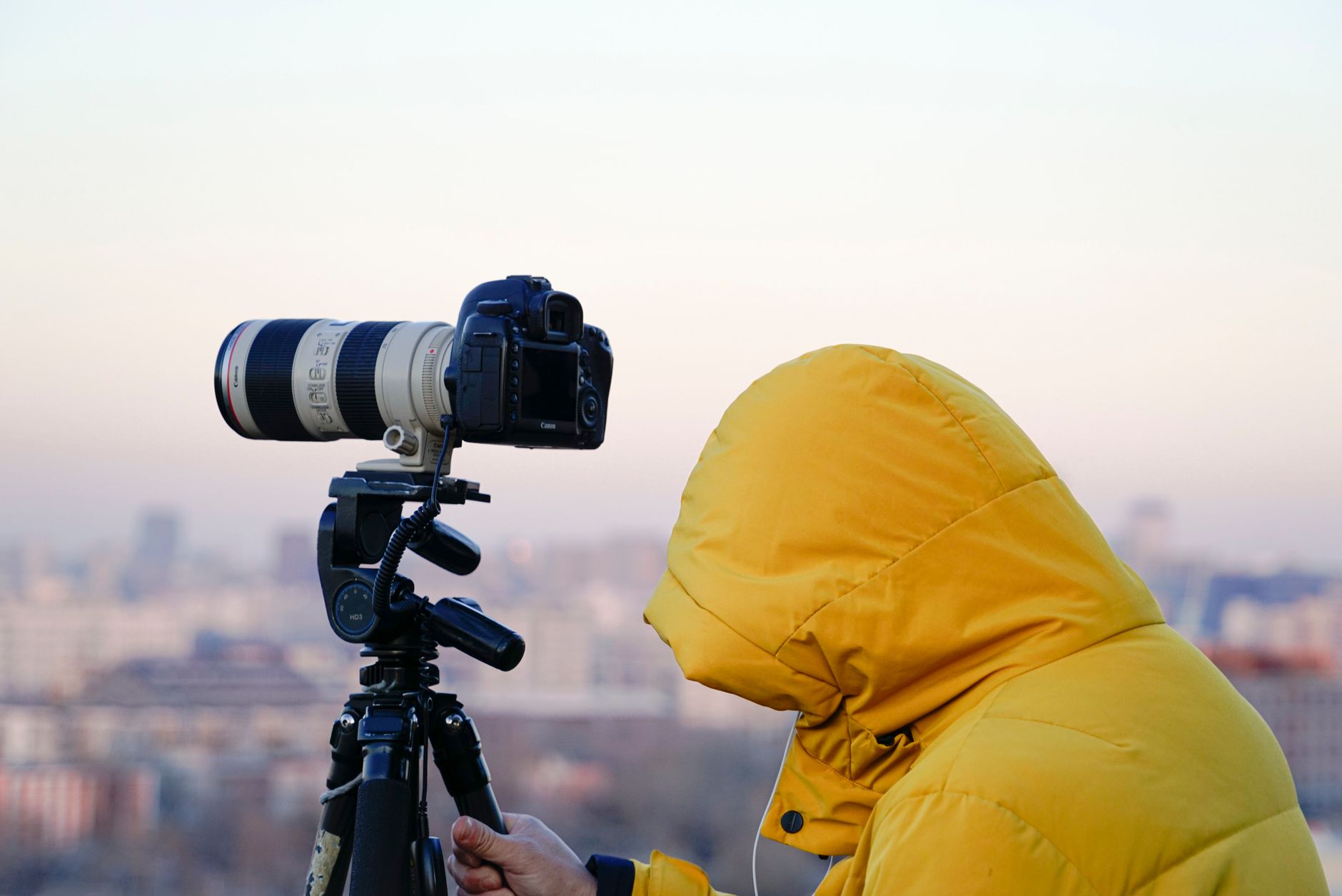 A photographer working from a tripod to shoot a Chinese city skyline at dusk