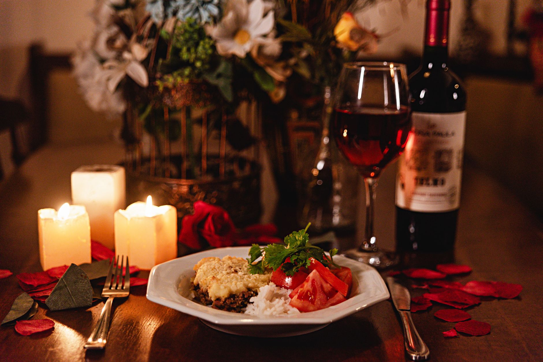 Candlelit dinner table laid for two with wine glasses and warm lighting