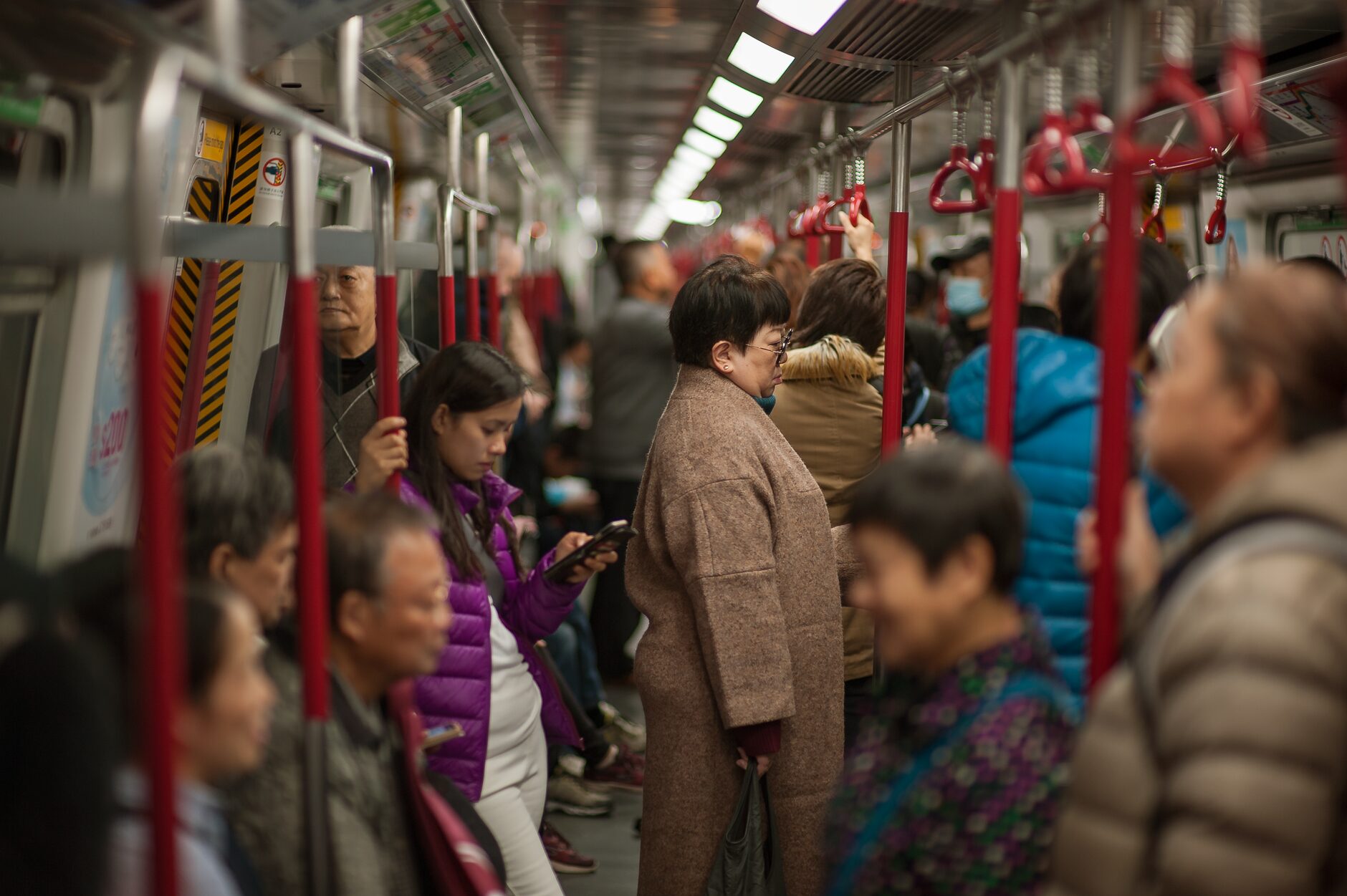 Passengers standing and seated inside a crowded Asian metro carriage