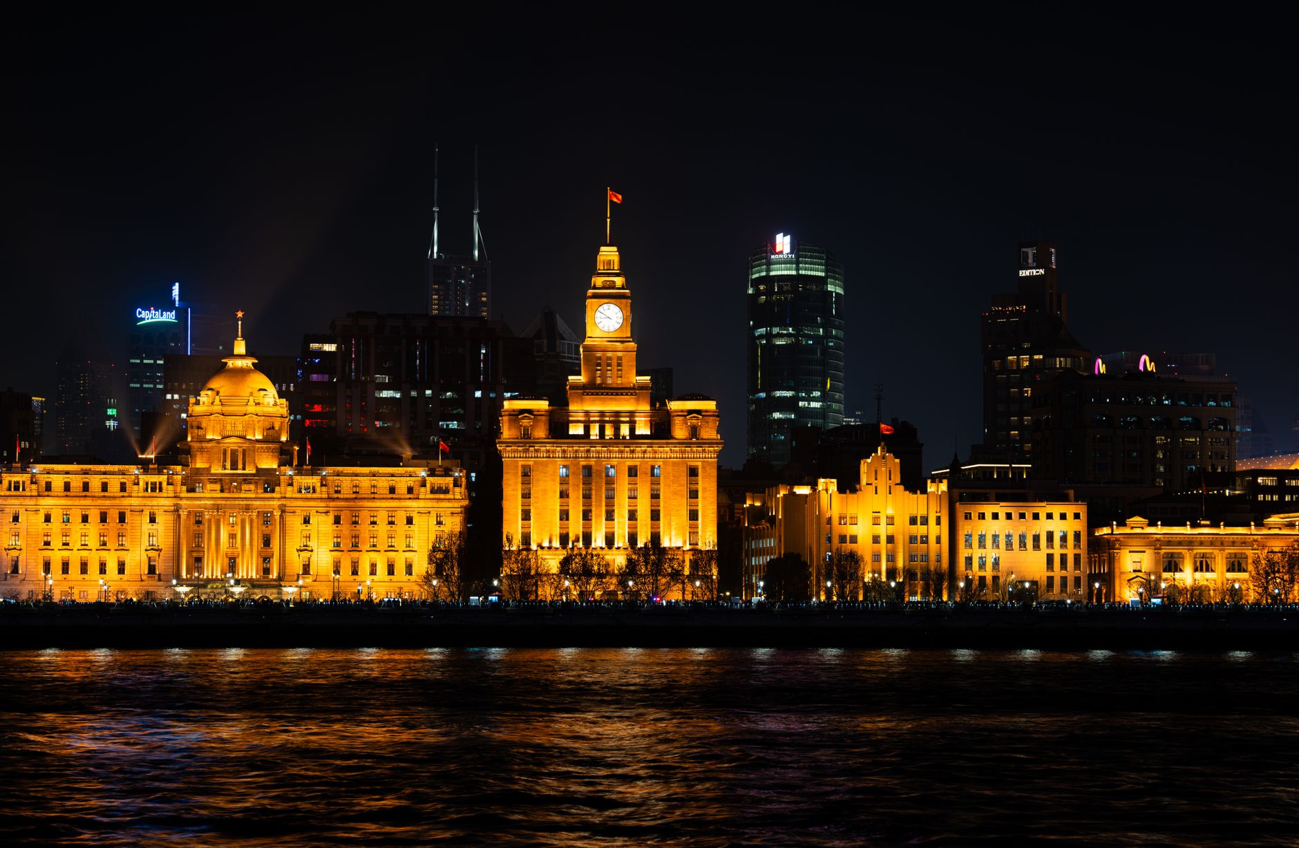 Historic waterfront buildings lit up and mirrored in the river after dark