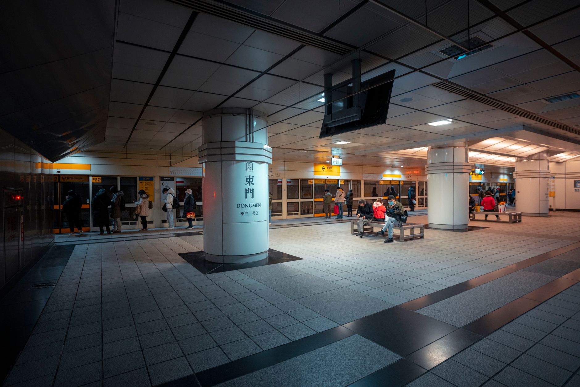 Passengers waiting on a brightly lit Chinese metro platform at night, safe transport for solo travellers