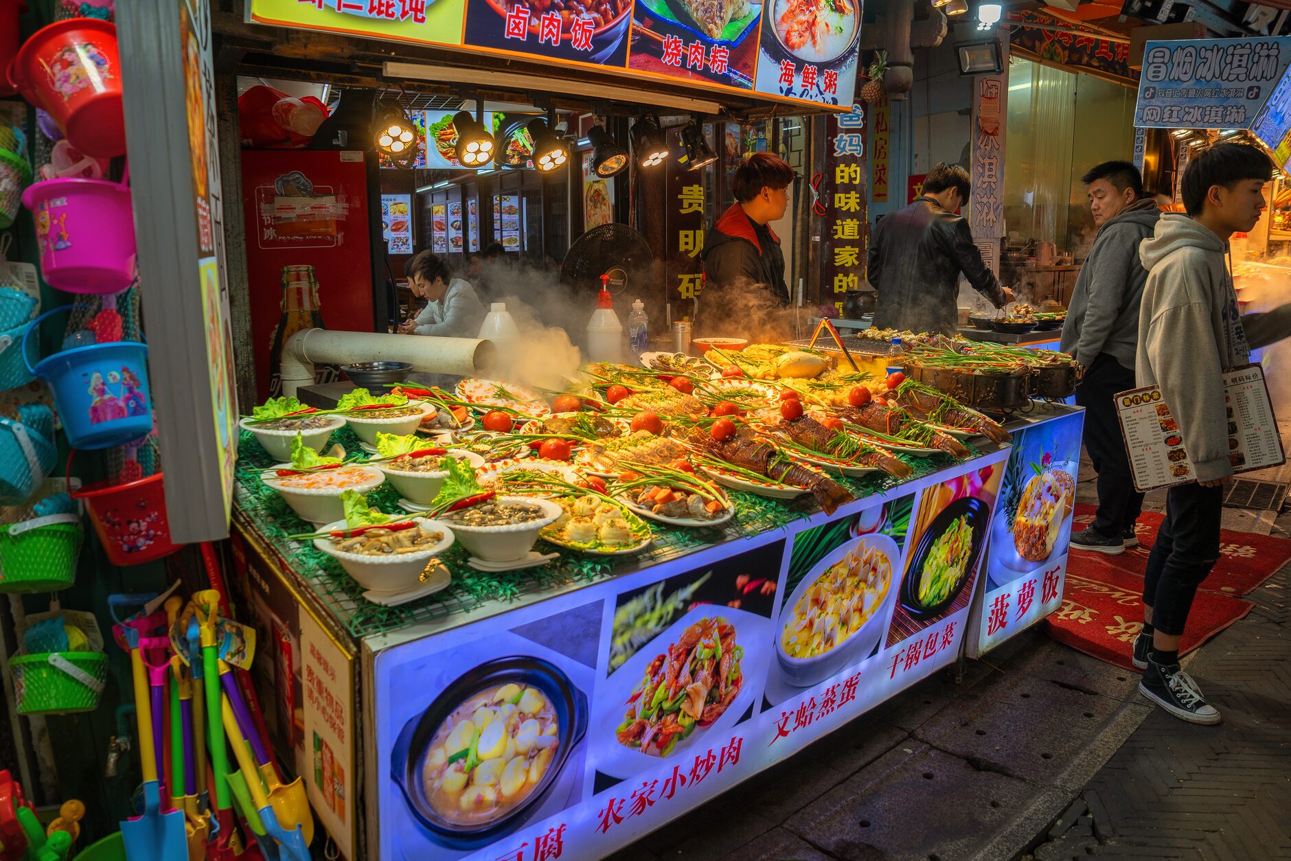 A night market food stall in China with a wide spread of hot street-food dishes