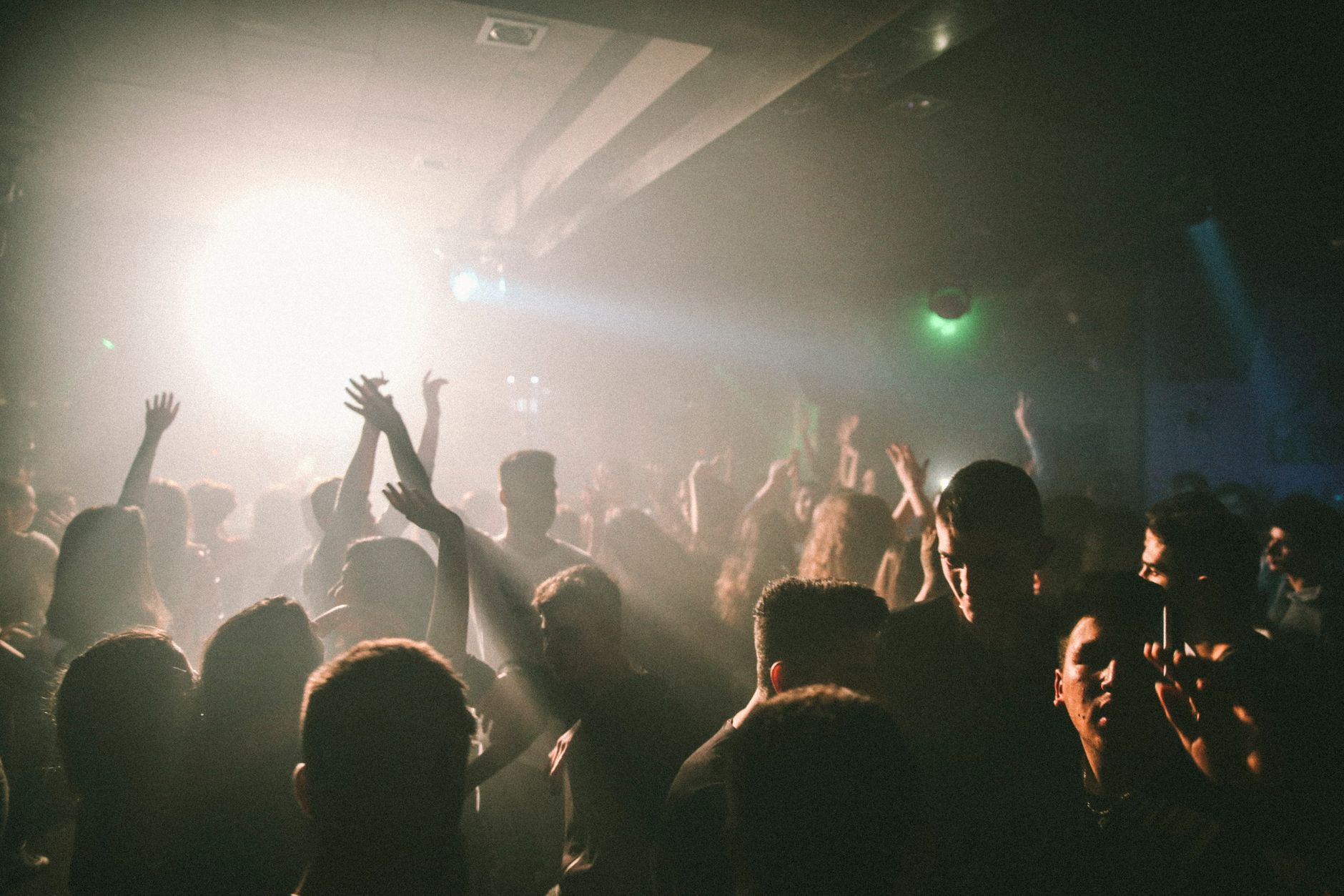 Clubbers dancing under coloured lights on a packed nightclub dance floor, typical of a Shanghai weekend