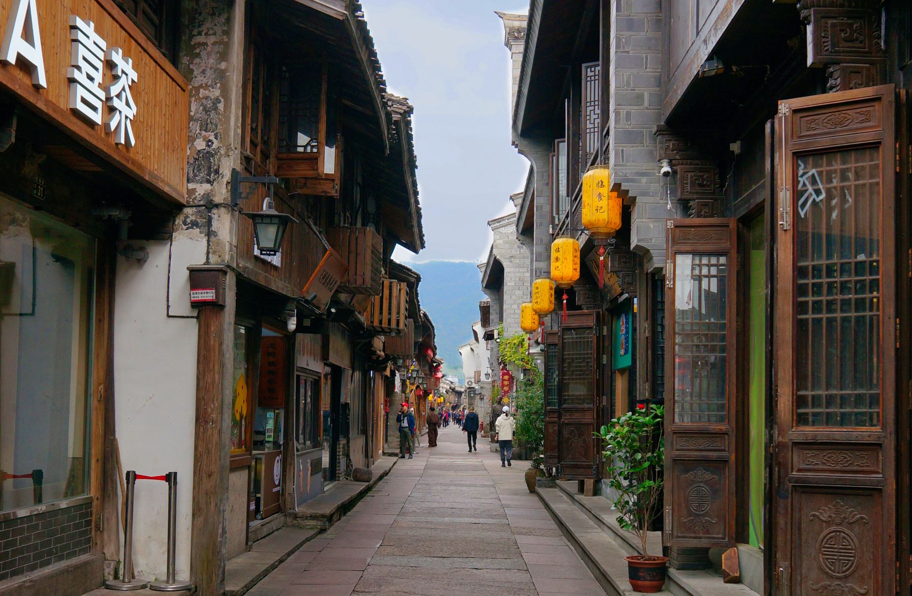 A narrow lane of low old houses hung with lanterns in a Chinese city