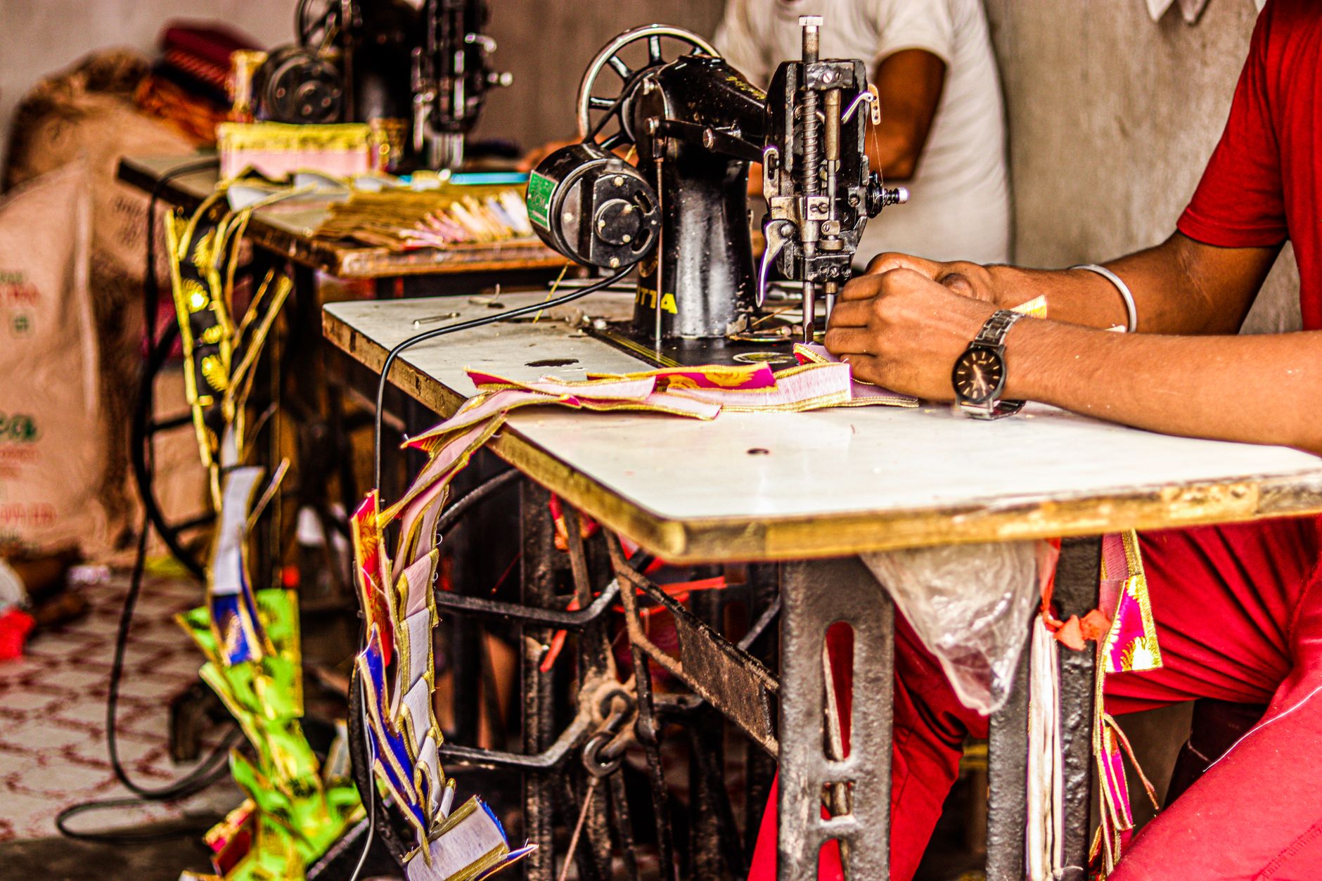 A tailor stitching fabric on an industrial sewing machine in a workshop