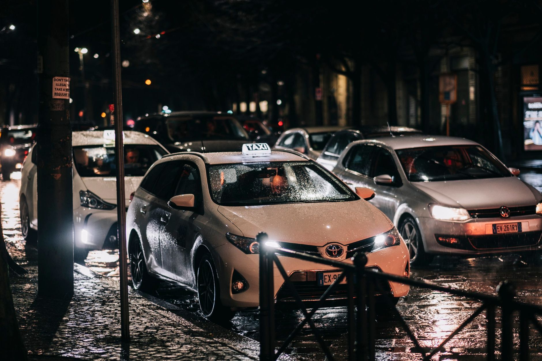 Taxis and traffic on a wet city street at night with reflected lights