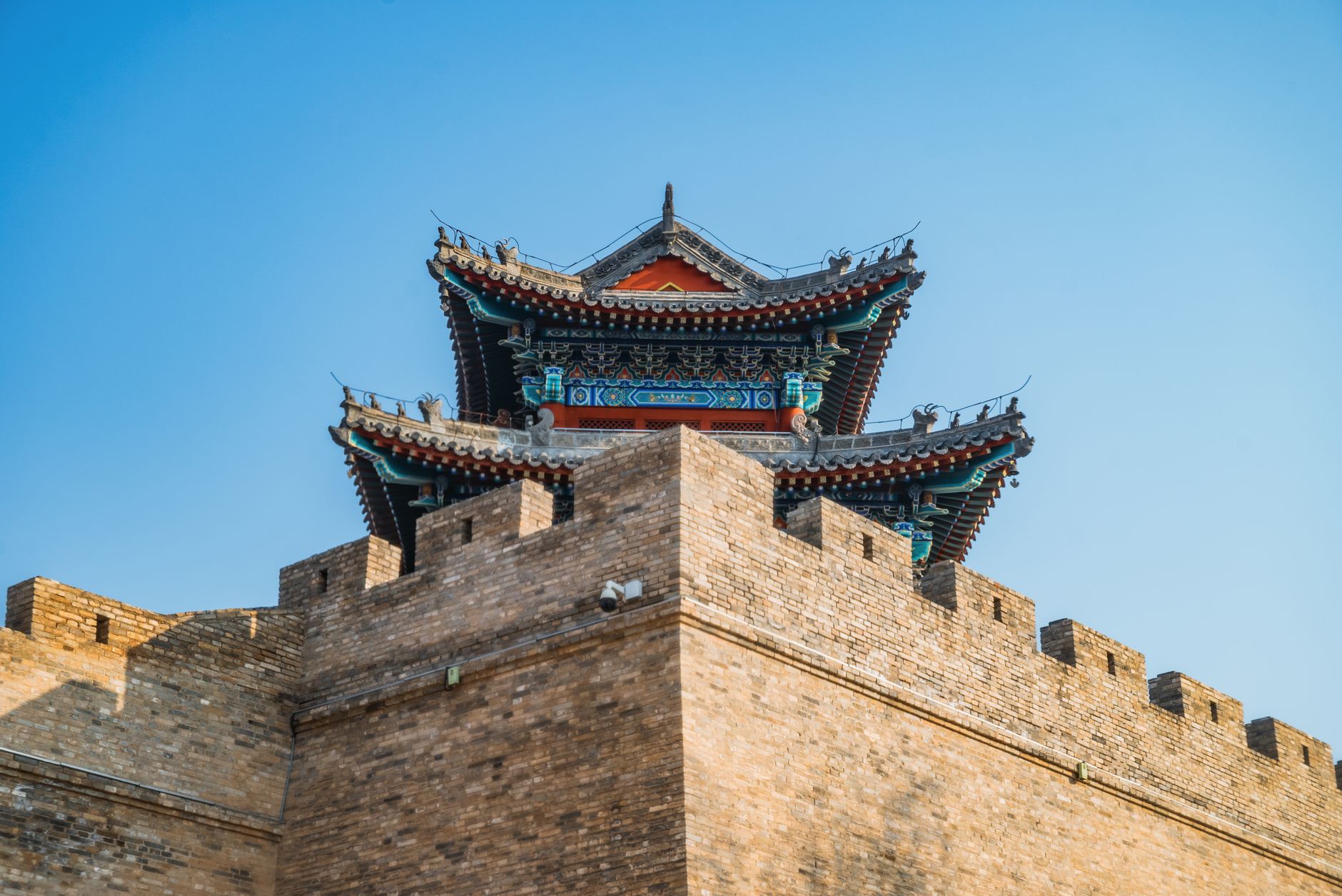 A gate tower rising above a stretch of ancient Chinese city wall