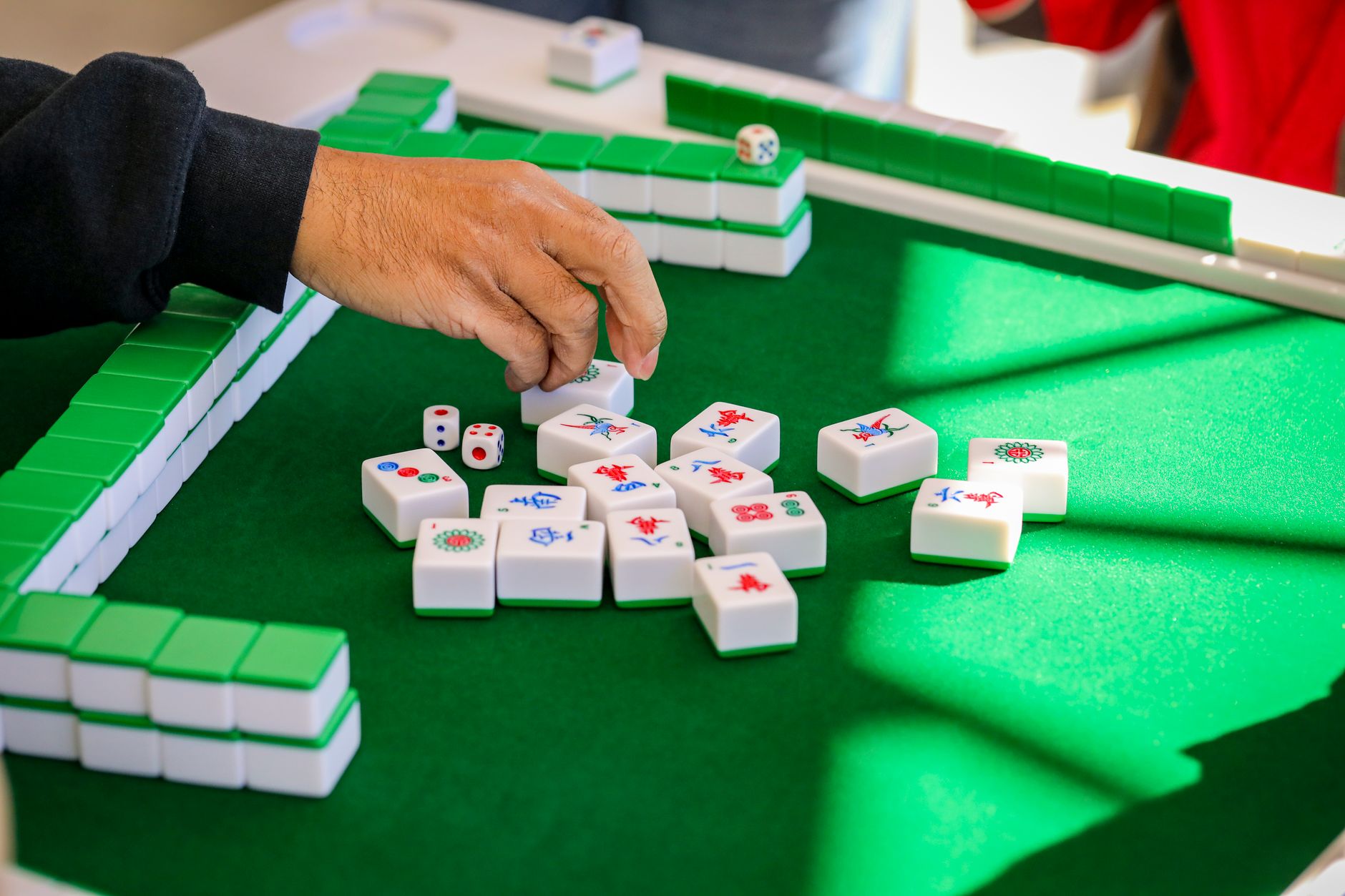 Hands arranging mahjong tiles during a game, a fixture of Shanghai lane life