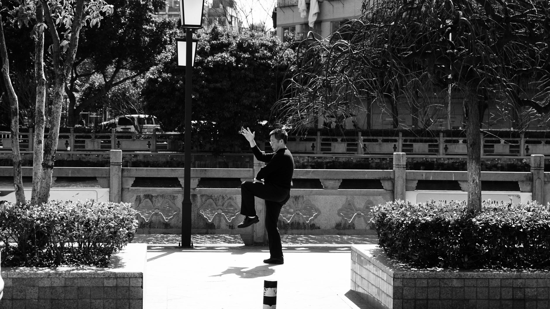 A man practising tai chi in a Chinese urban park early in the morning