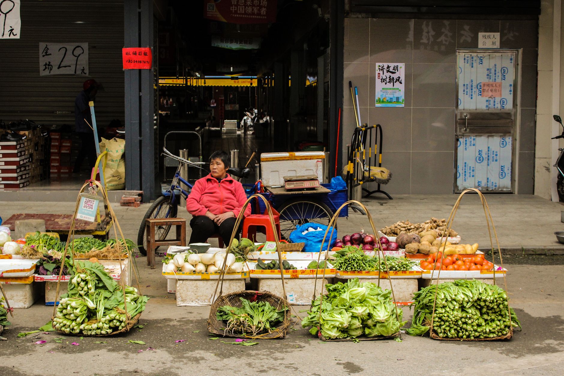 A street vendor in China selling fresh leafy greens and vegetables at a neighbourhood market
