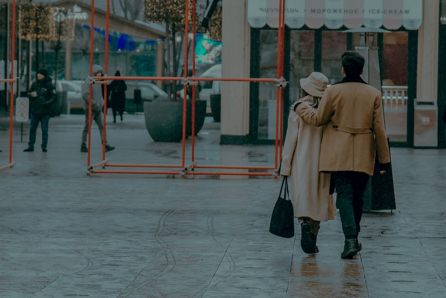 A couple in heavy coats walking through a modern city in cold winter rain, the weather Shanghai gets most of December and January