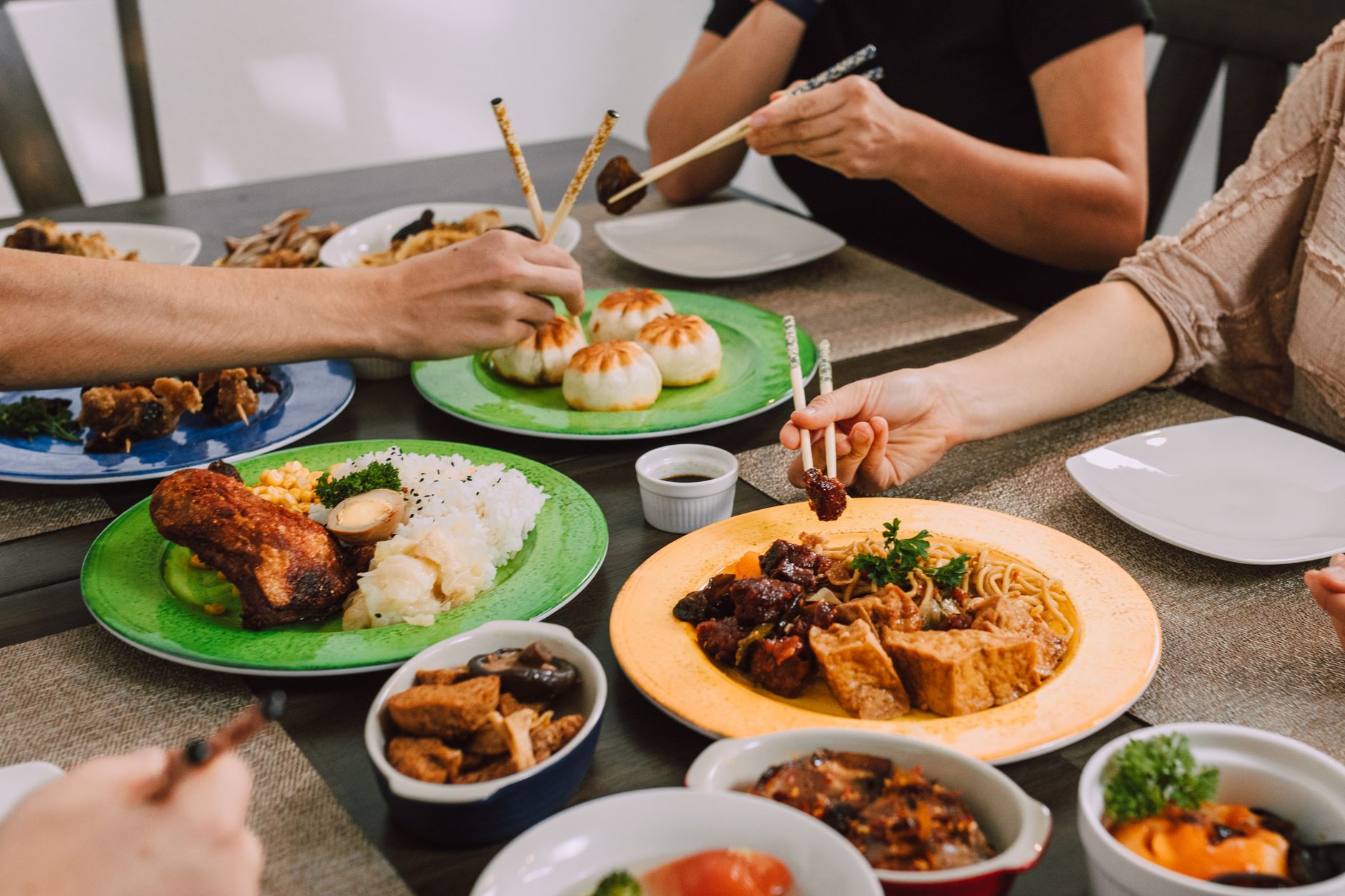 Diners sharing buns, noodles and rice dishes from the middle of a table