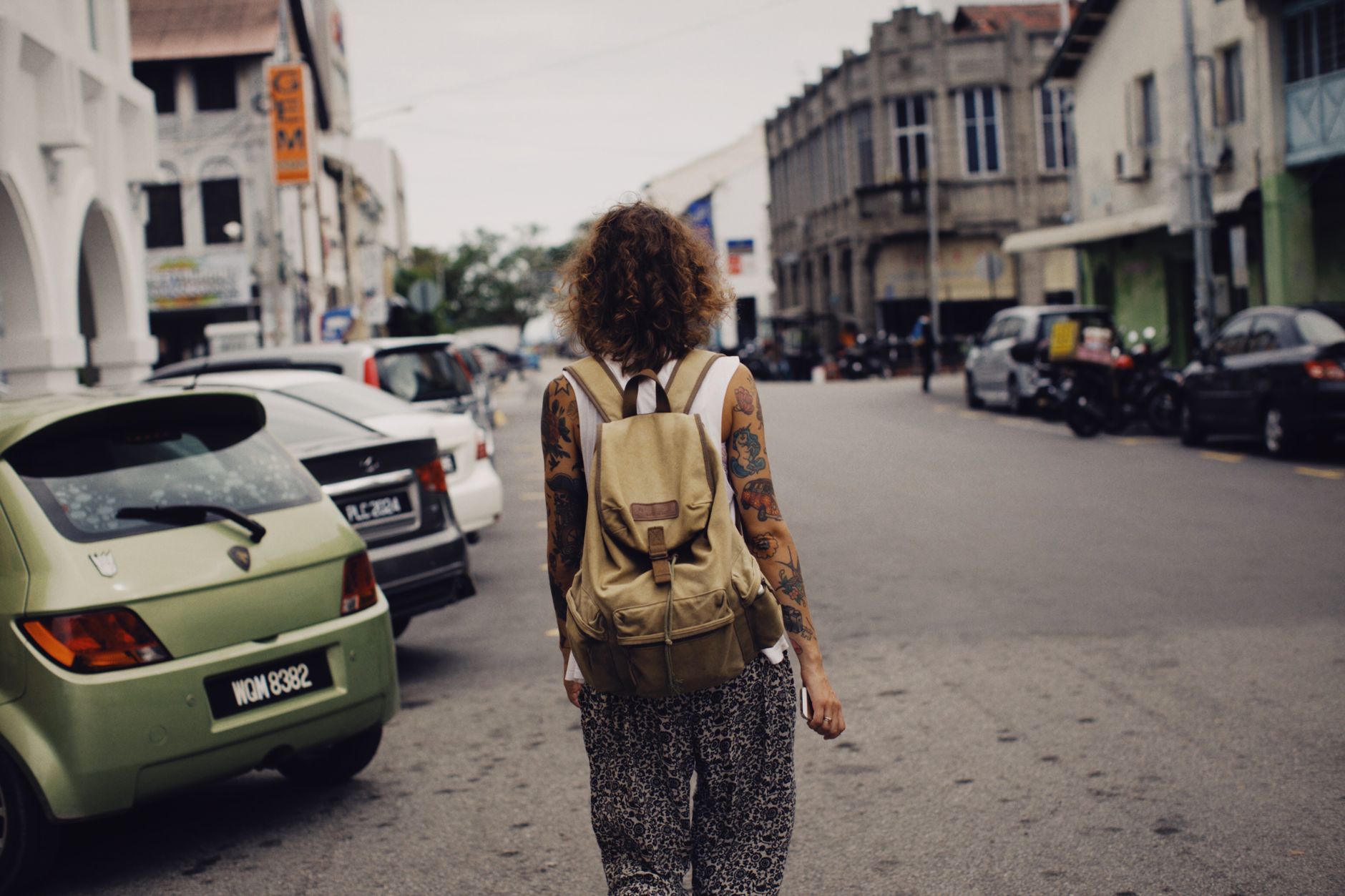 A young woman travelling alone with a backpack walking down a city street