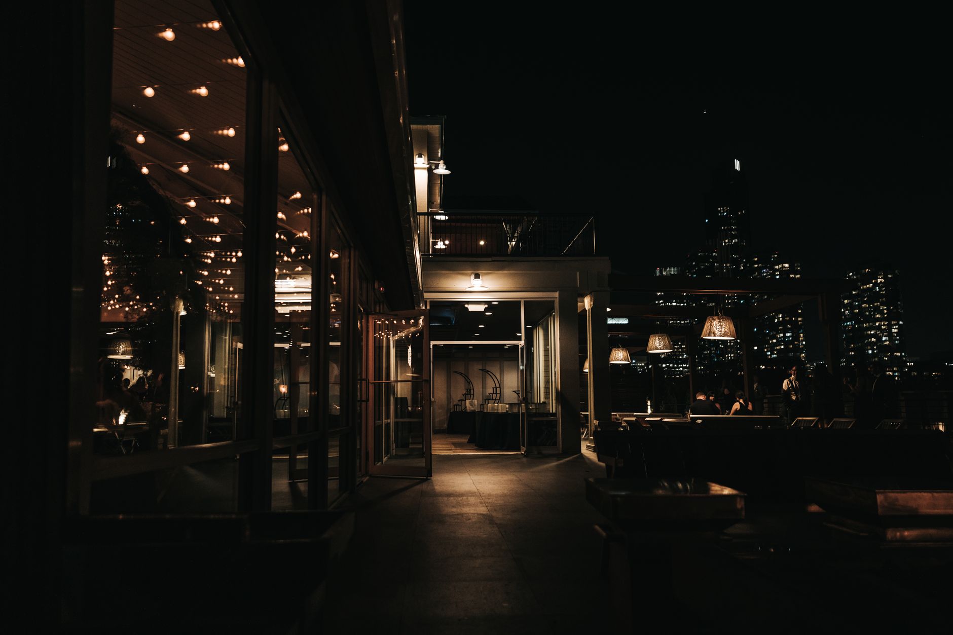 A rooftop bar terrace at night overlooking a lit city skyline, as found above the Bund