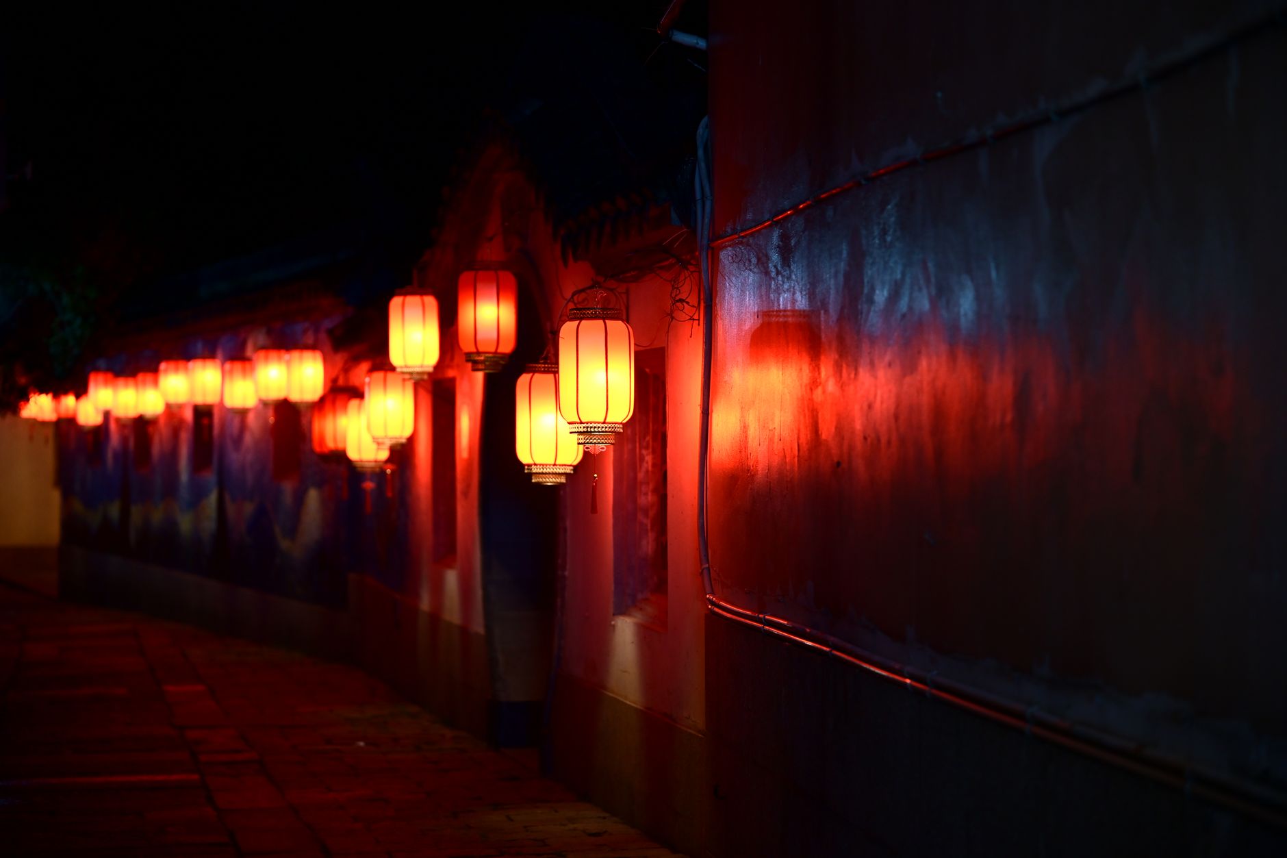 Red lanterns glowing above a narrow old-town lane after dark in eastern China