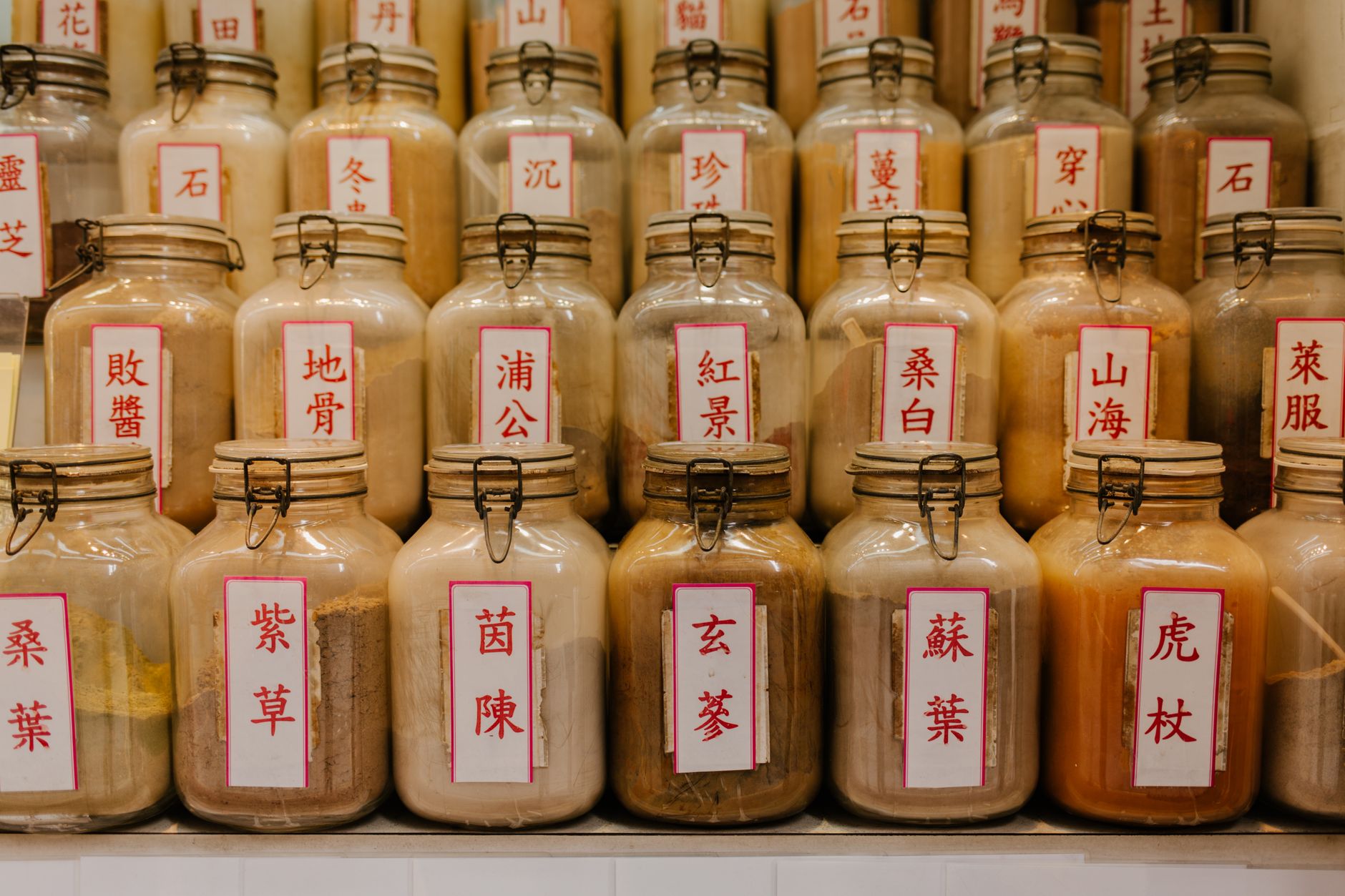 Jars of dried herbs with Chinese labels on the shelves of a traditional Chinese medicine shop