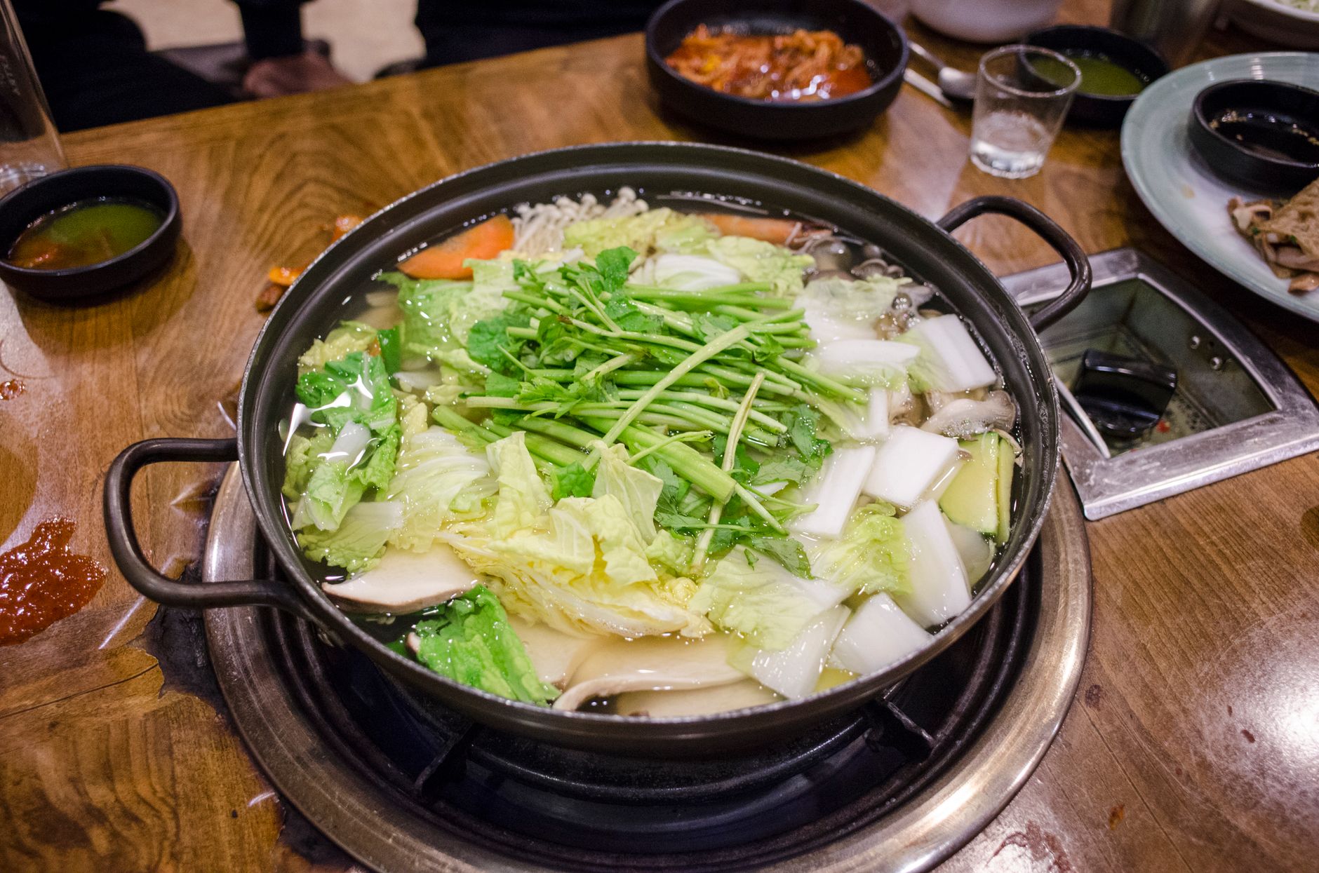 A vegetable hot pot with fresh greens, mushrooms and tofu, the easiest vegan option at a Chinese hotpot table