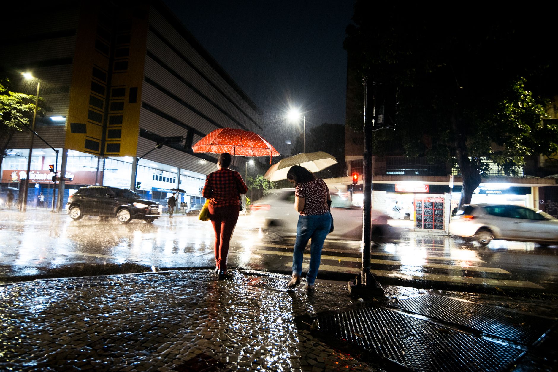 Pedestrians with umbrellas on a wet city street during the rainy season