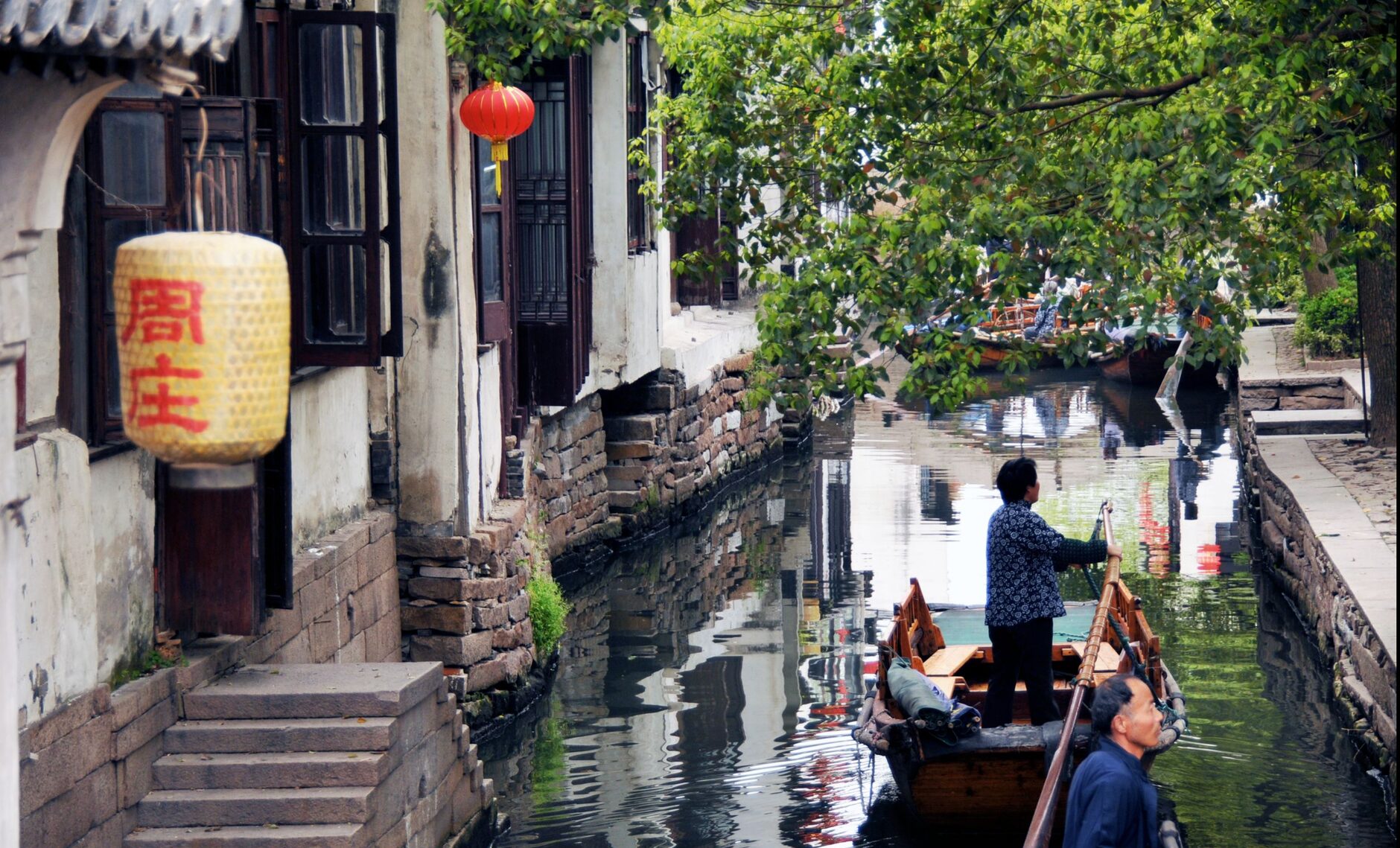 A traditional wooden boat on a canal lined with red lanterns in a Chinese water town