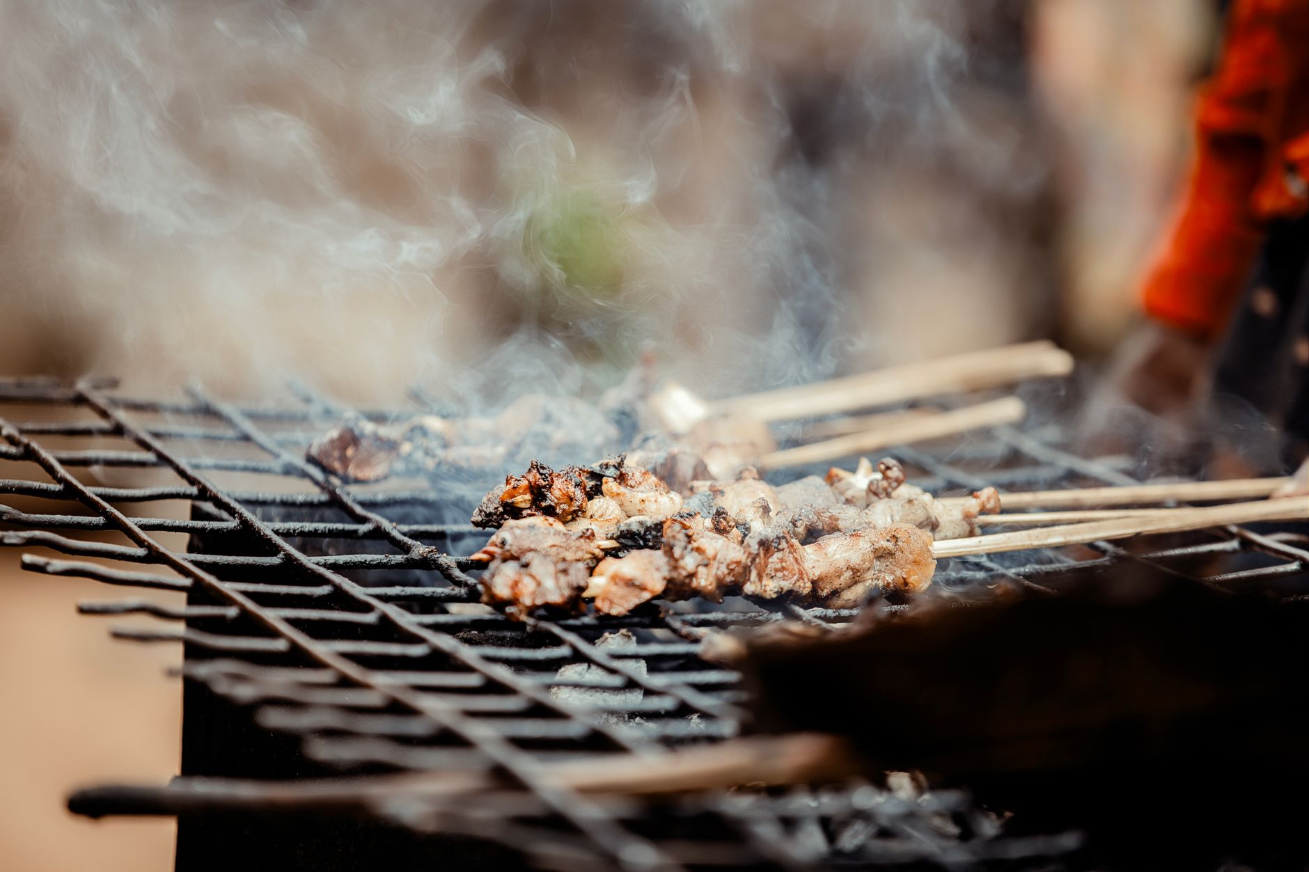 Lamb skewers grilling over charcoal with smoke rising