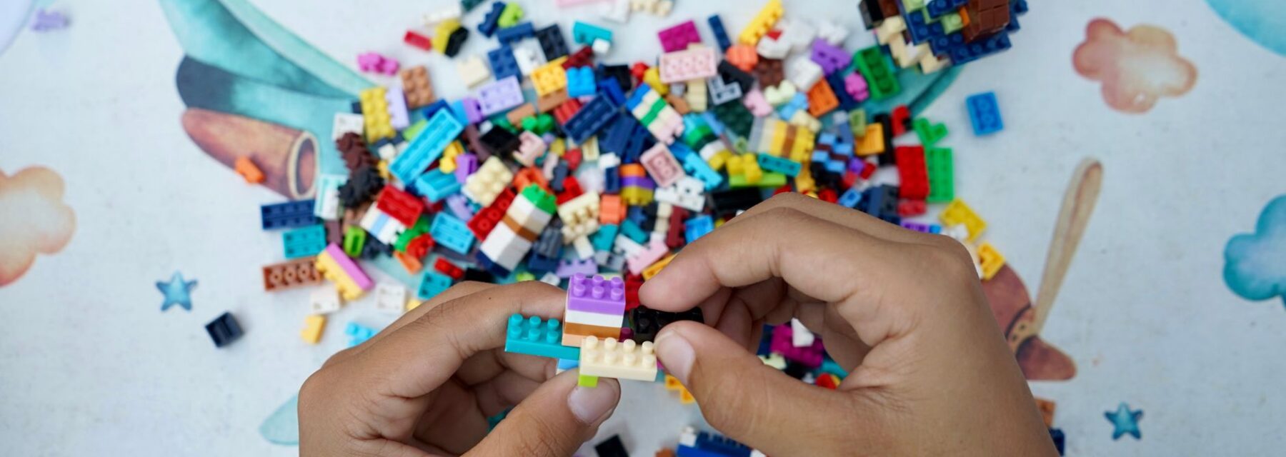 A child's hands assembling colourful plastic building bricks on a table