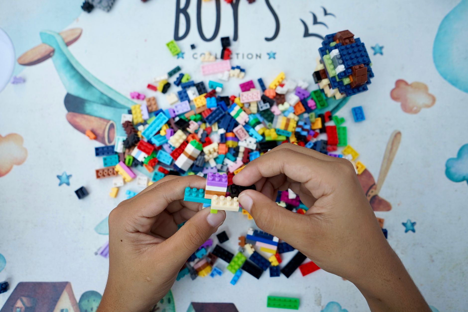 A child's hands assembling colourful plastic building bricks on a table