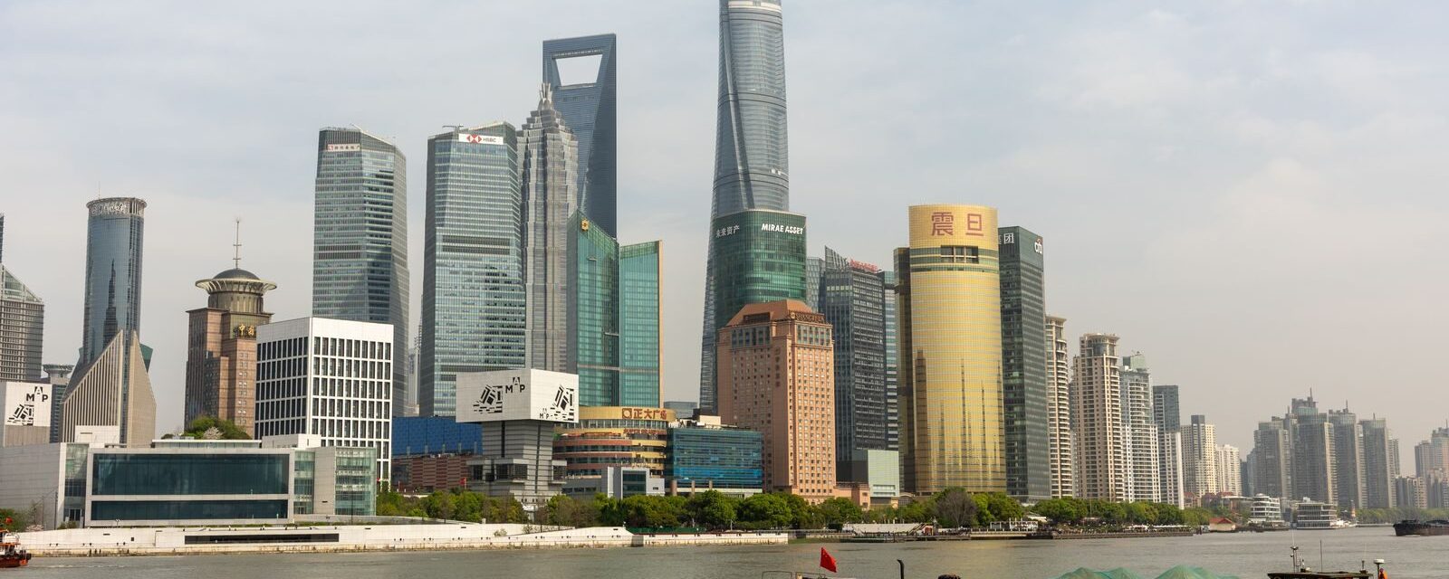 Lujiazui skyline in Pudong seen from across the Huangpu River with a barge passing