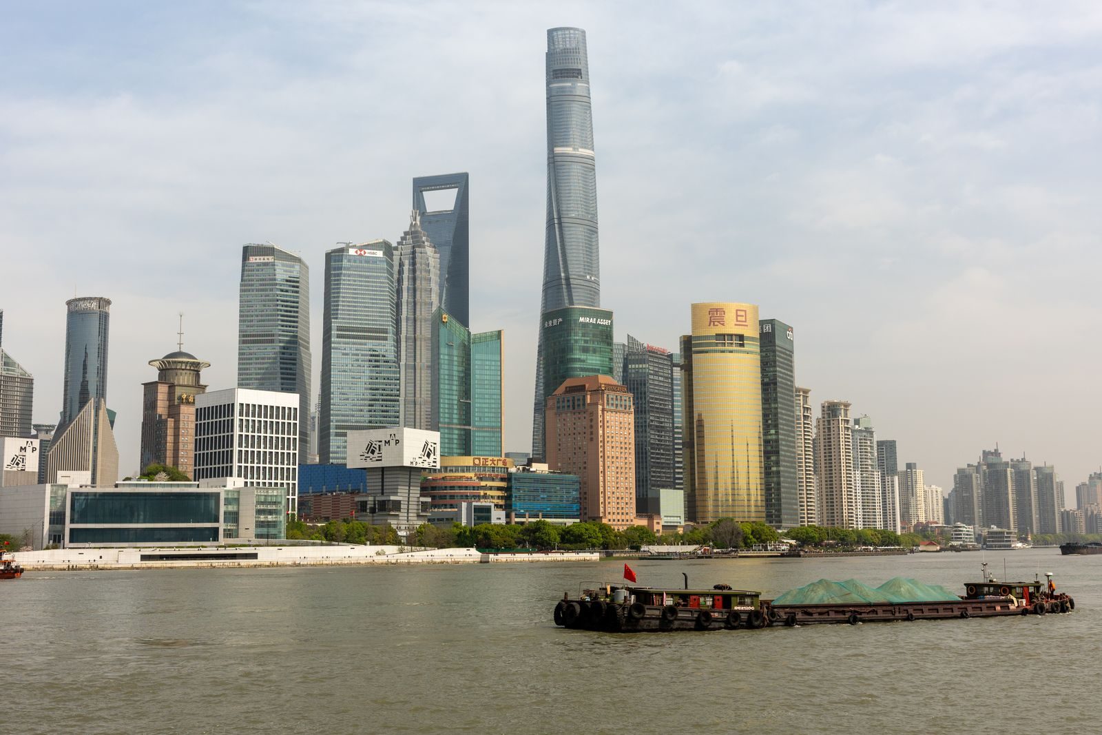 Lujiazui skyline in Pudong seen from across the Huangpu River with a barge passing