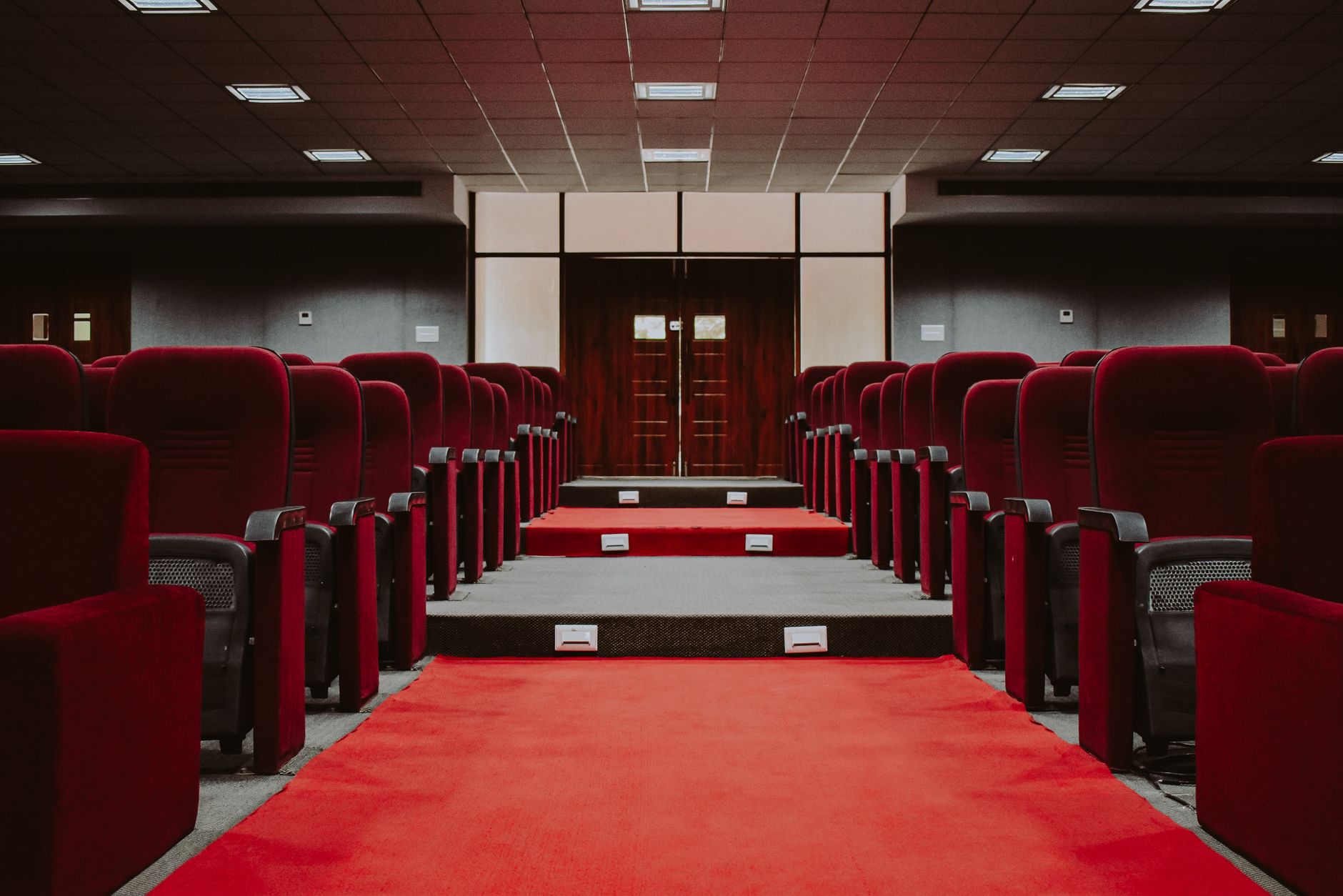 Rows of red velvet theatre seats seen from the back of an auditorium