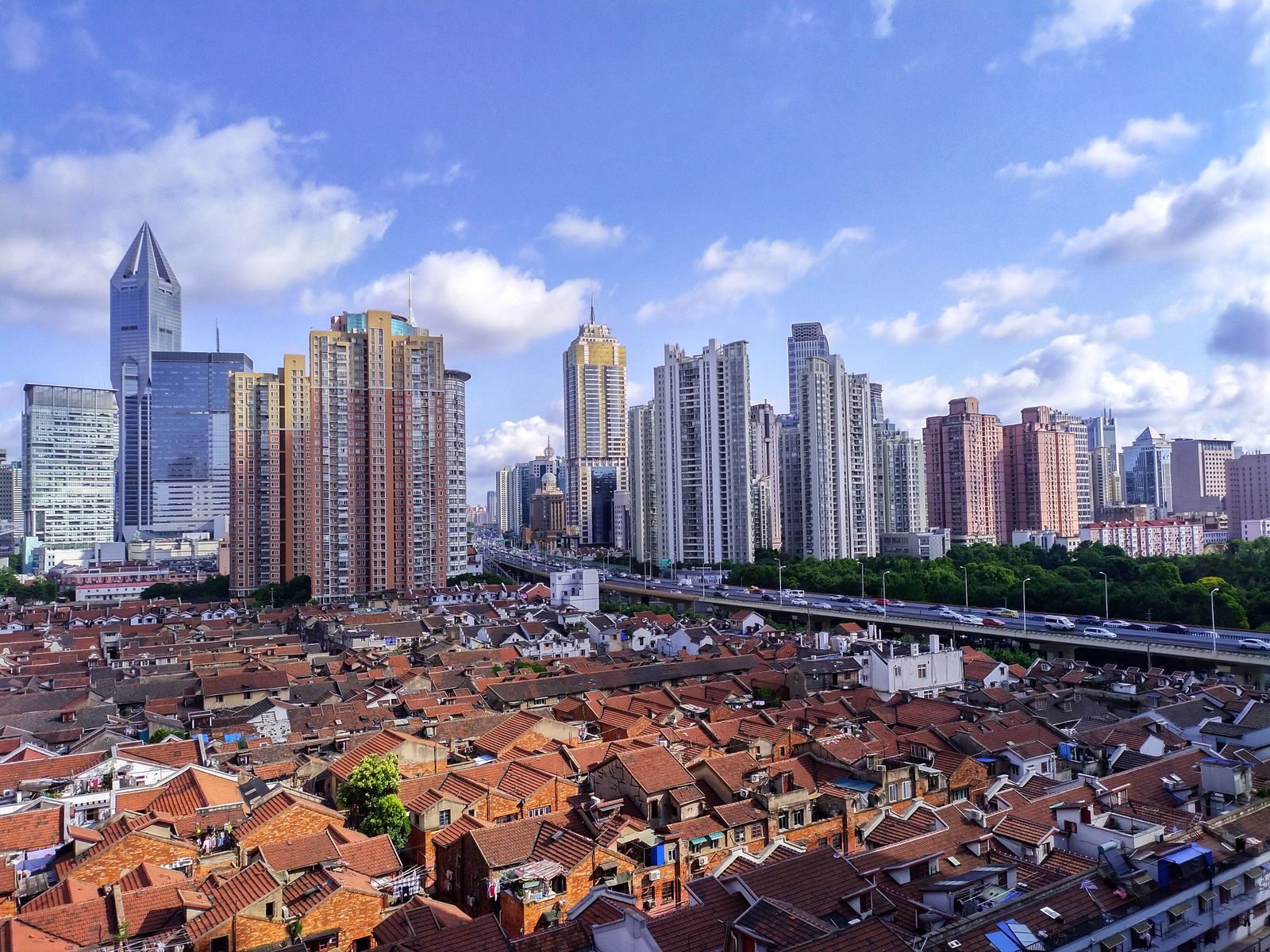 Tiled roofs of Shanghai's old lane houses in Puxi with modern high-rise districts behind them