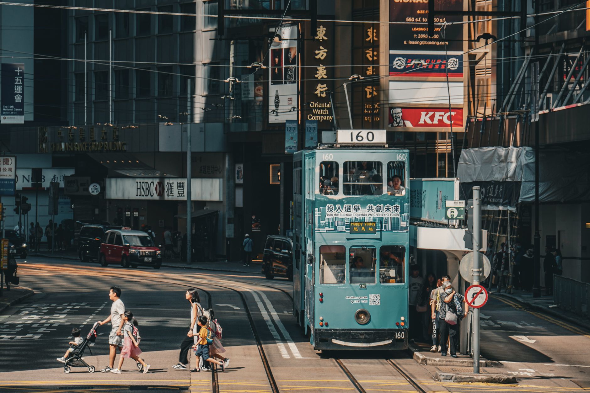 A double-decker tram on a Hong Kong street with Chinese and English shop signage