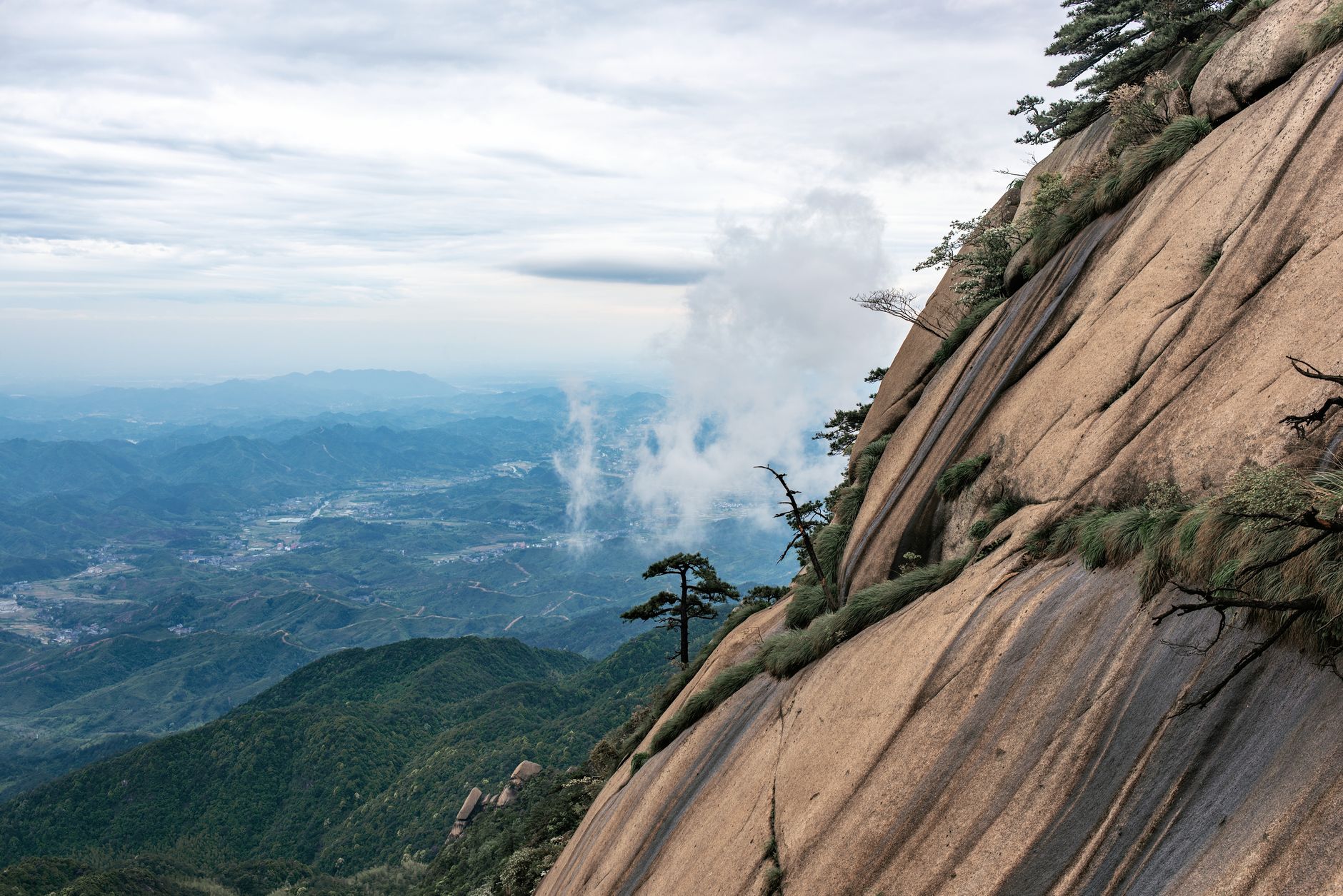A granite cliff face on Huangshan with a lone pine and the valley far below