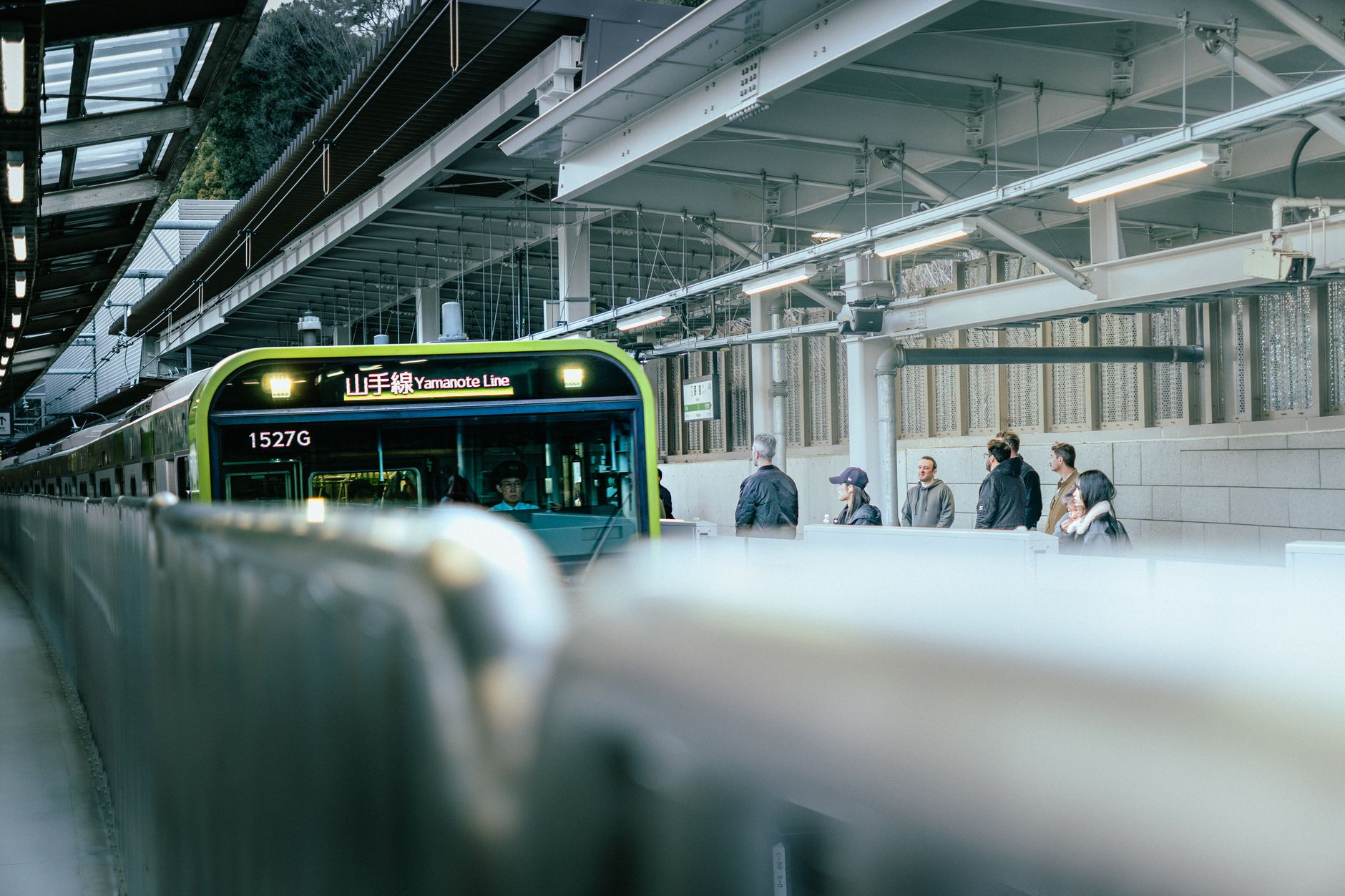A Yamanote Line train at a platform in Tokyo with passengers waiting