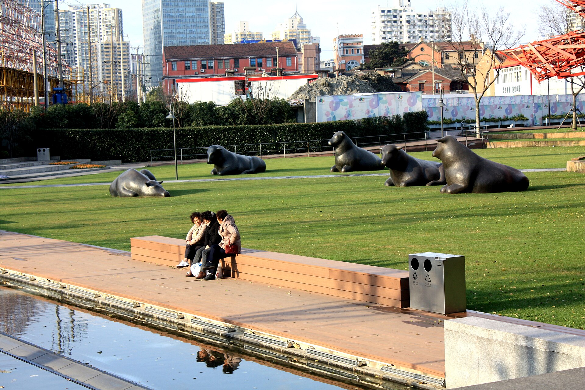 Bronze animal sculptures on a lawn in Jing'an Sculpture Park with office towers behind