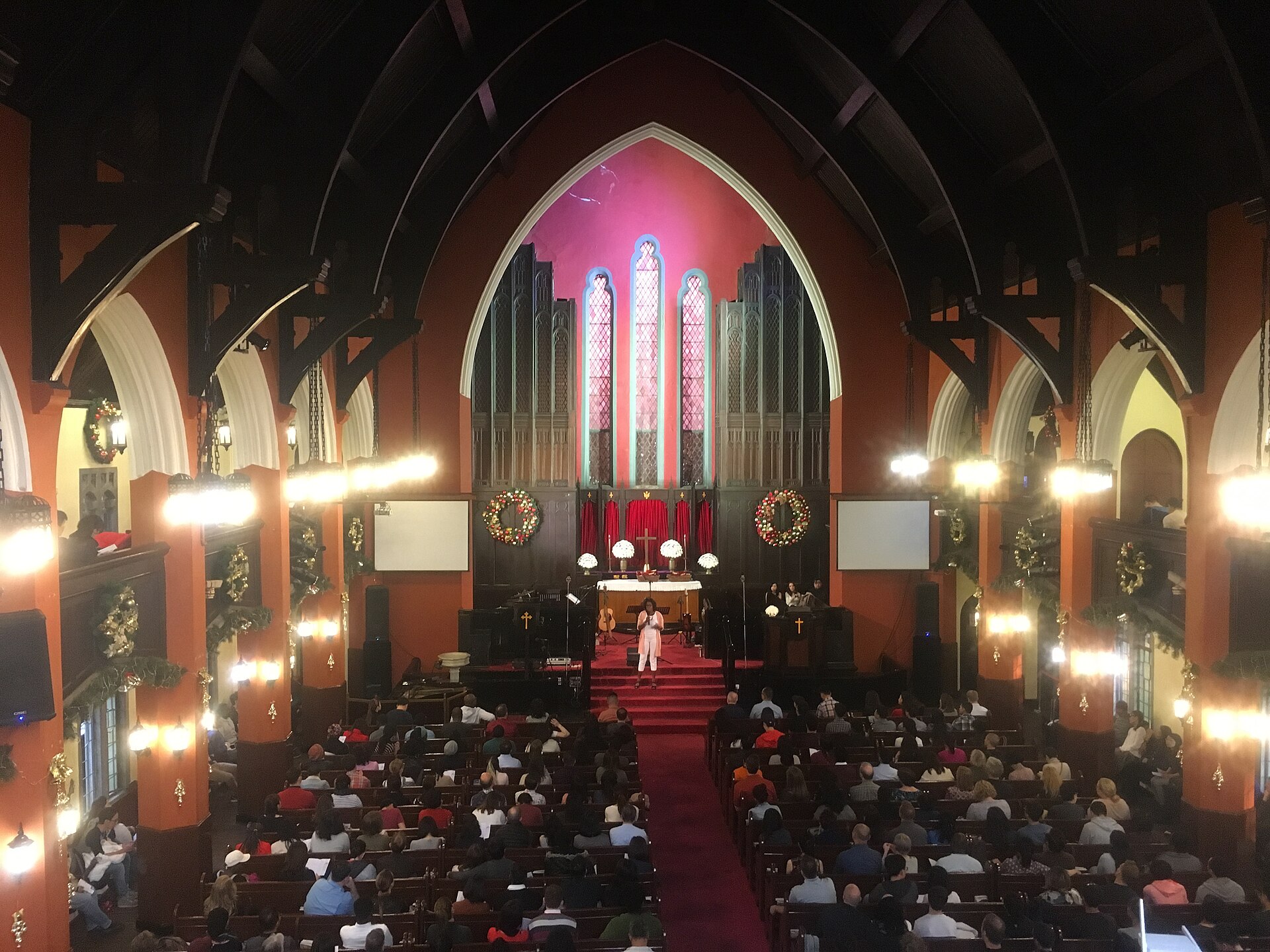 A full congregation inside the Community Church on Hengshan Road, with wreaths on the walls and an organ behind the altar