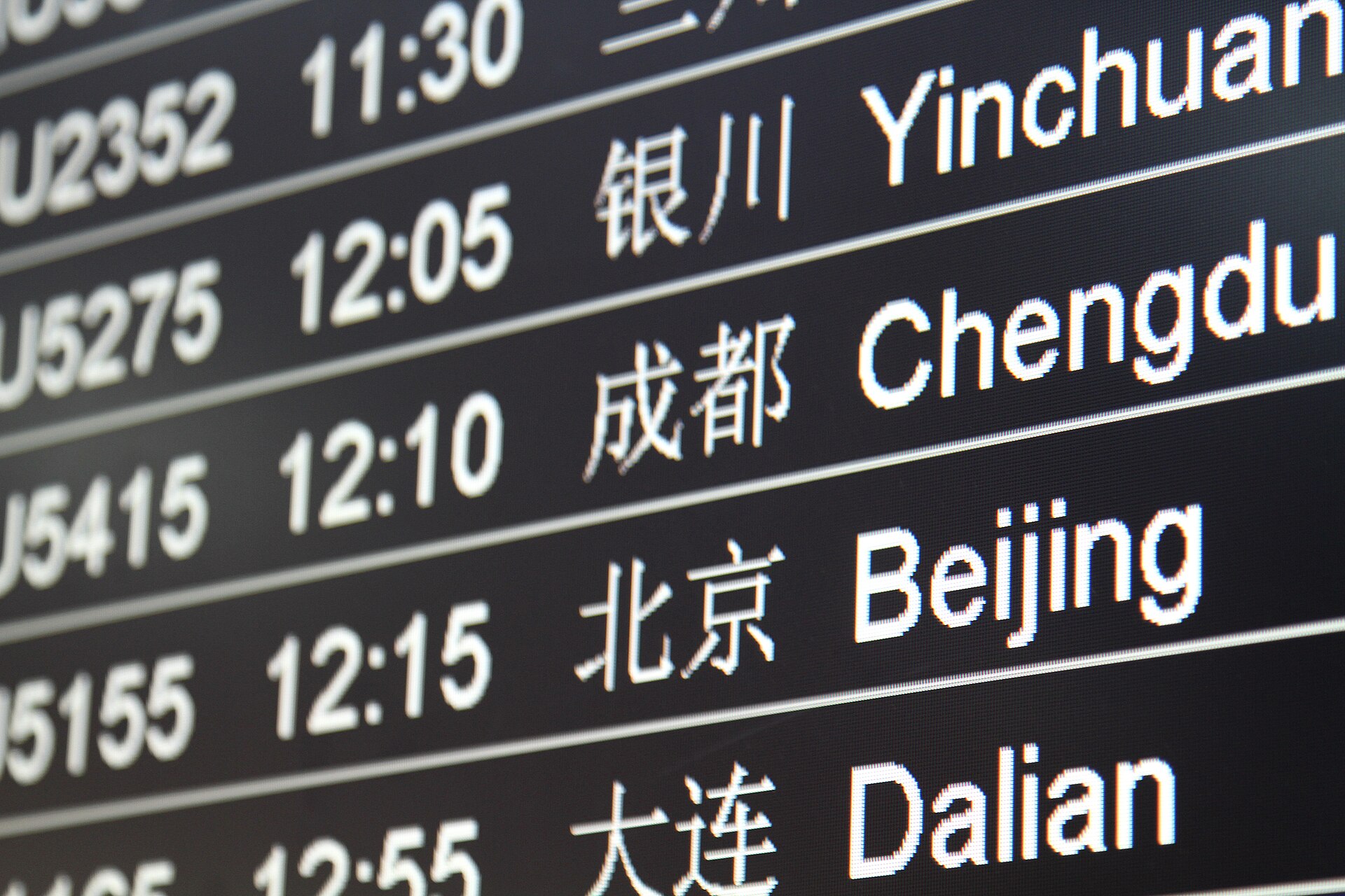 A flight information board at Shanghai Pudong Airport lists Yinchuan, Chengdu, Beijing and Dalian in Chinese and English.