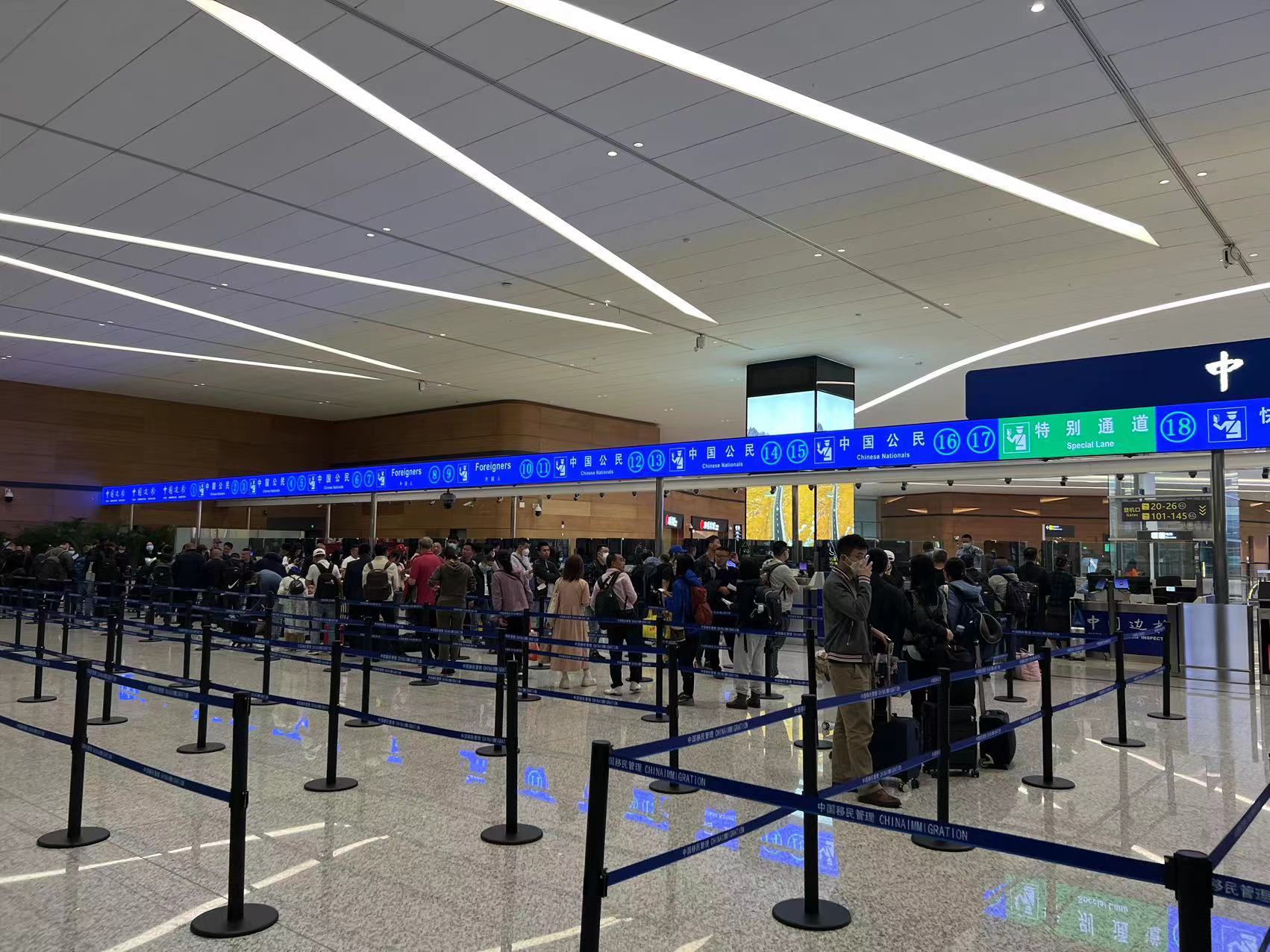 Passengers queue between blue barriers before numbered immigration counters at Chengdu Tianfu Airport Terminal 2.