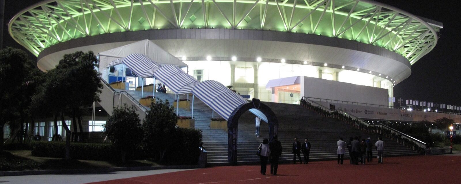 Center Court at the Qizhong Tennis Center in Shanghai lit up at night, its steel petal roof frame glowing green